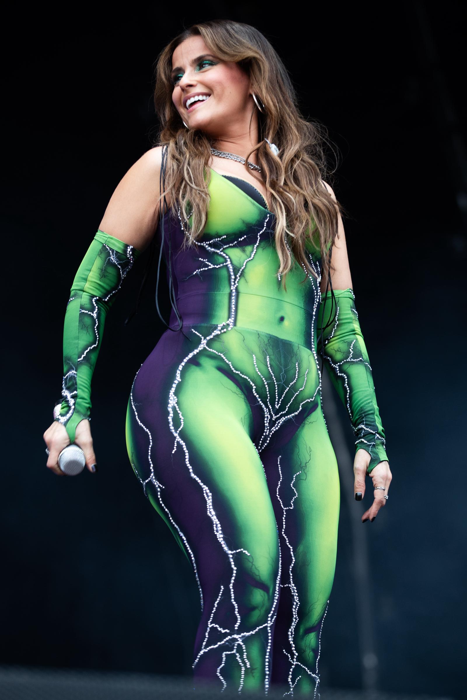 Nelly Furtado lights up the stage in a vibrant green-and-purple bodysuit with lightning bolt embellishments at the 2024 Forbidden Fruit Festival in Dublin.