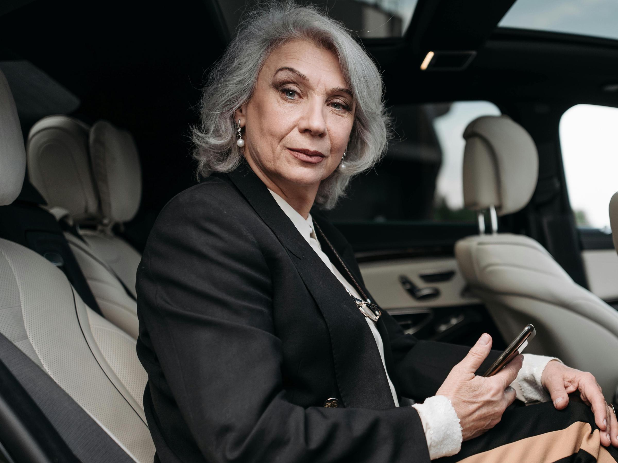 A elderly woman settling into the backseat of a vehicle | Source: Pexels