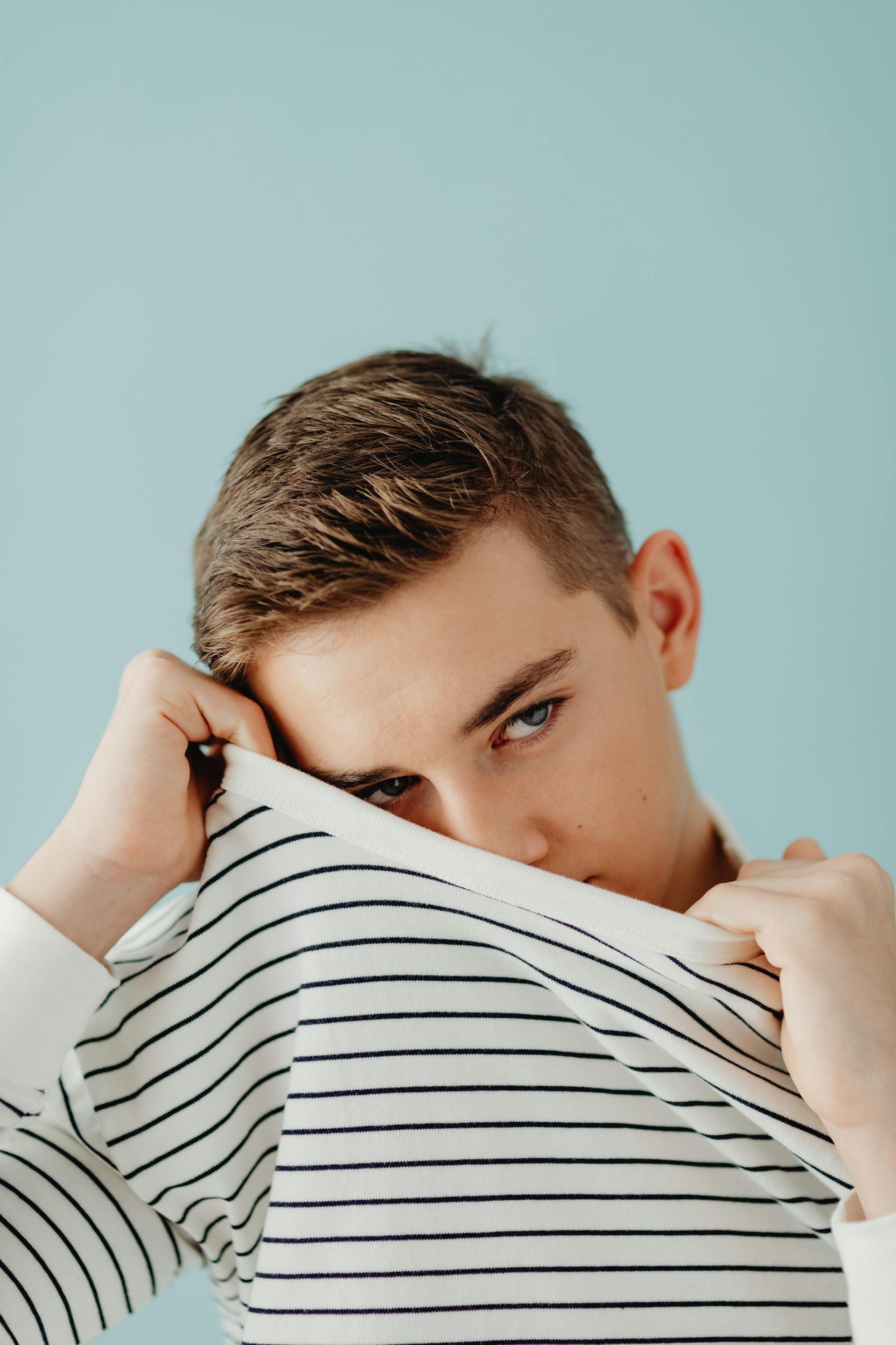 A nervous boy trying to cover his face | Source: Pexels