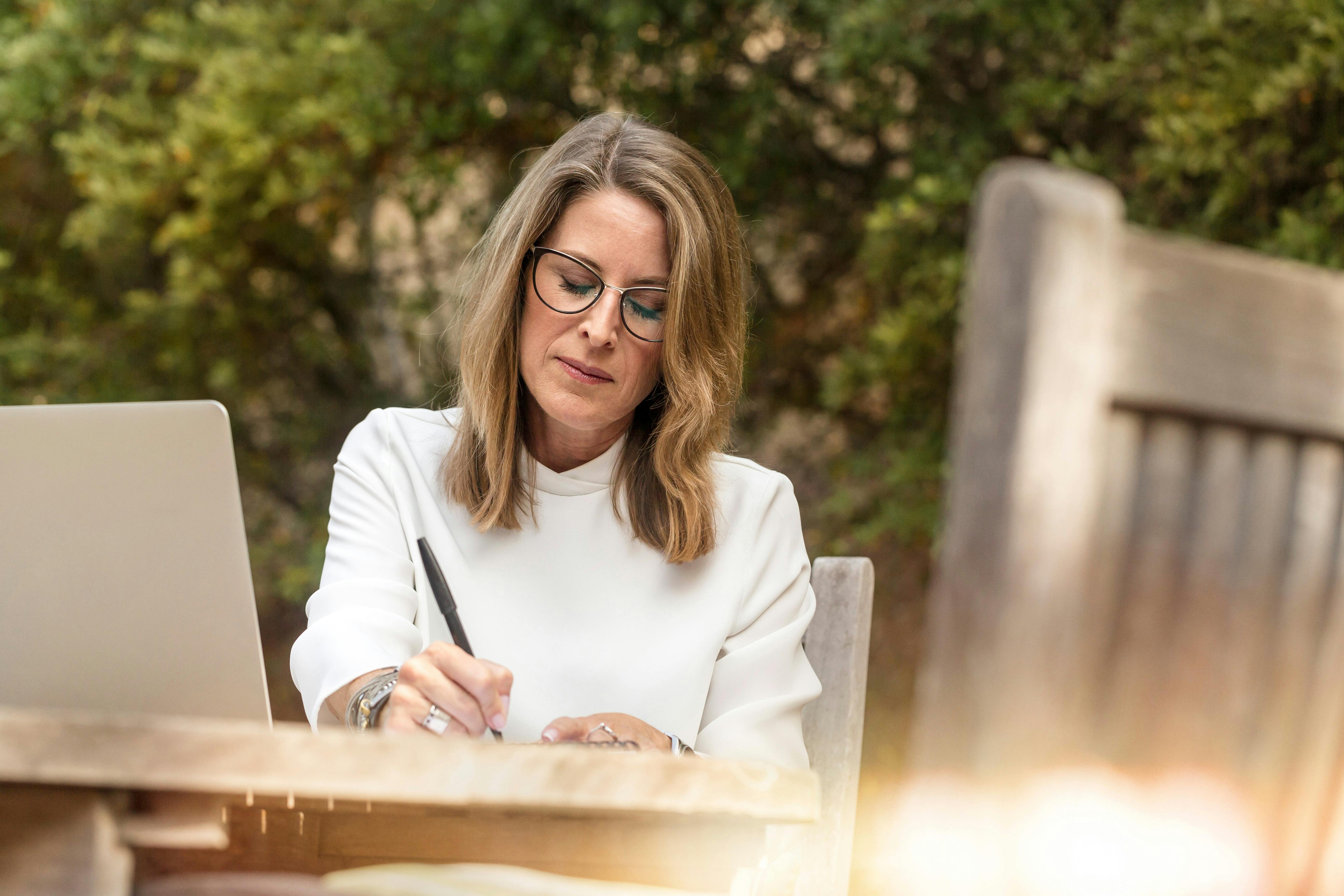 A woman writing on her garden table | Source: Pexels