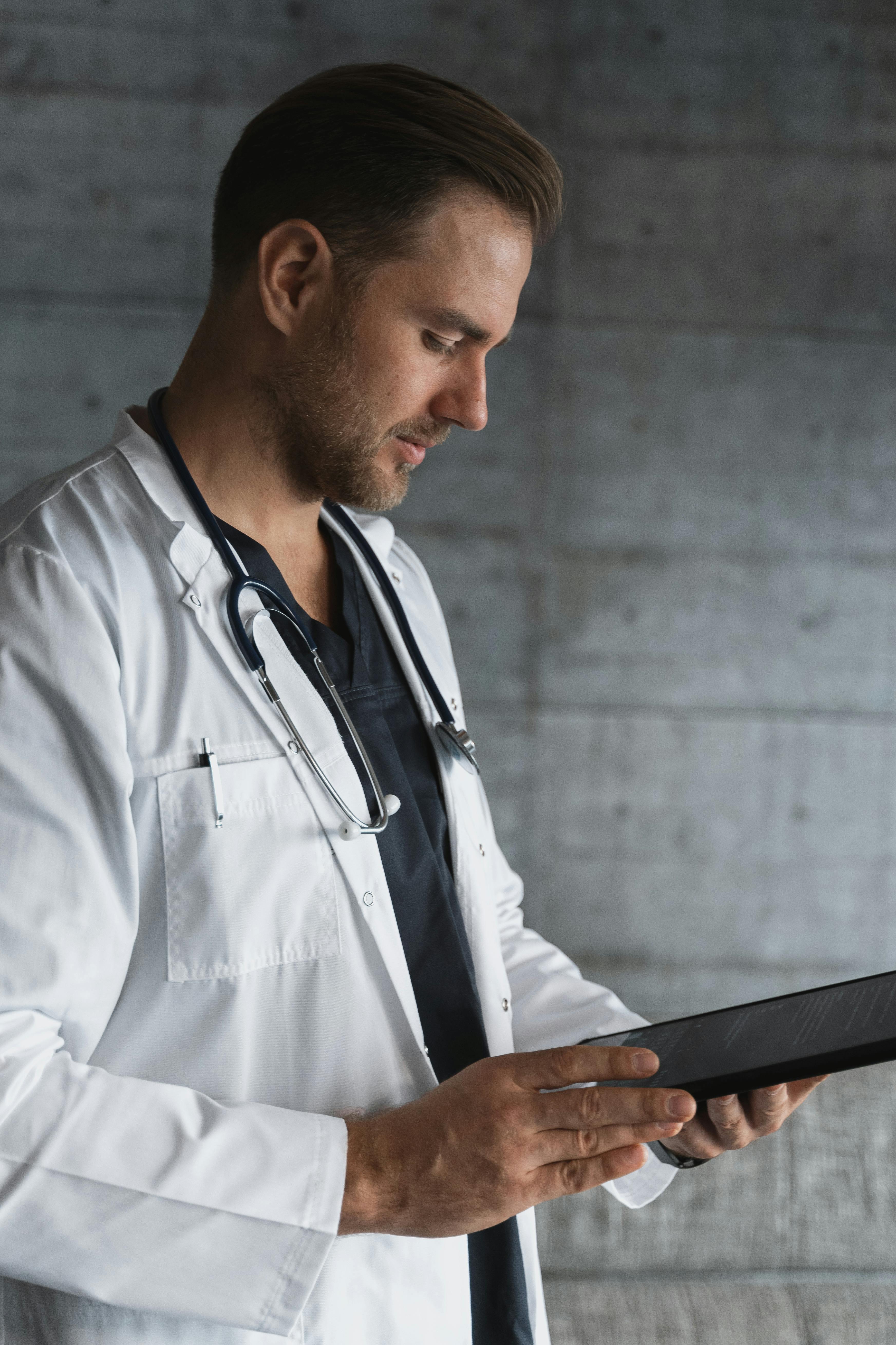 A doctor dress in a white coat while reading hospital documents | Source: Pexels