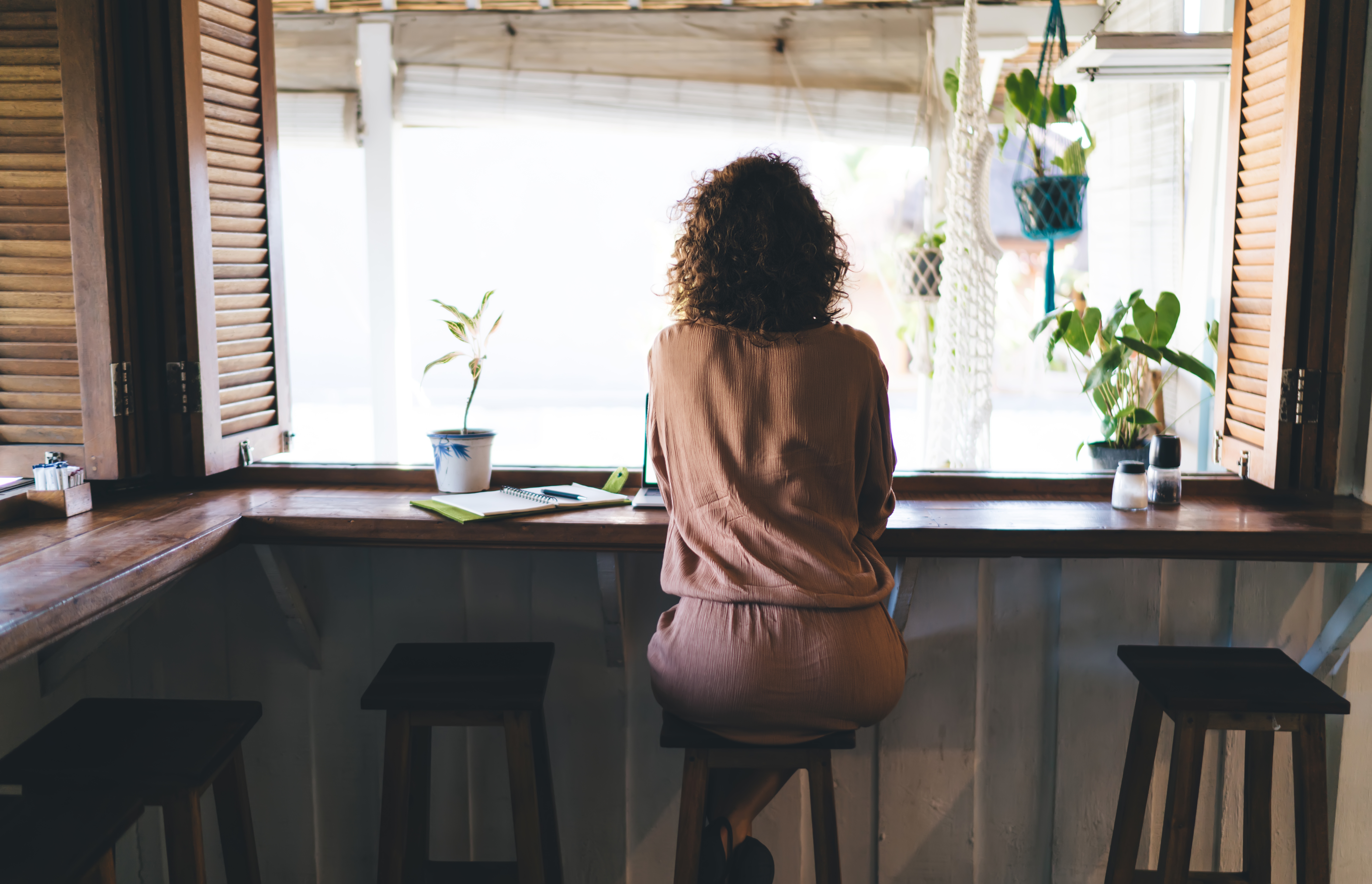 Back view of woman sitting at bar table at cafe. | Source: Shutterstock