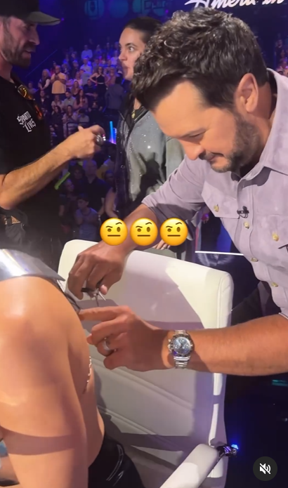 A screenshot captures Luke Bryan adjusting the back of Katy Perry's attire using a small pair of pliers. | Source: Instagram/katyperry