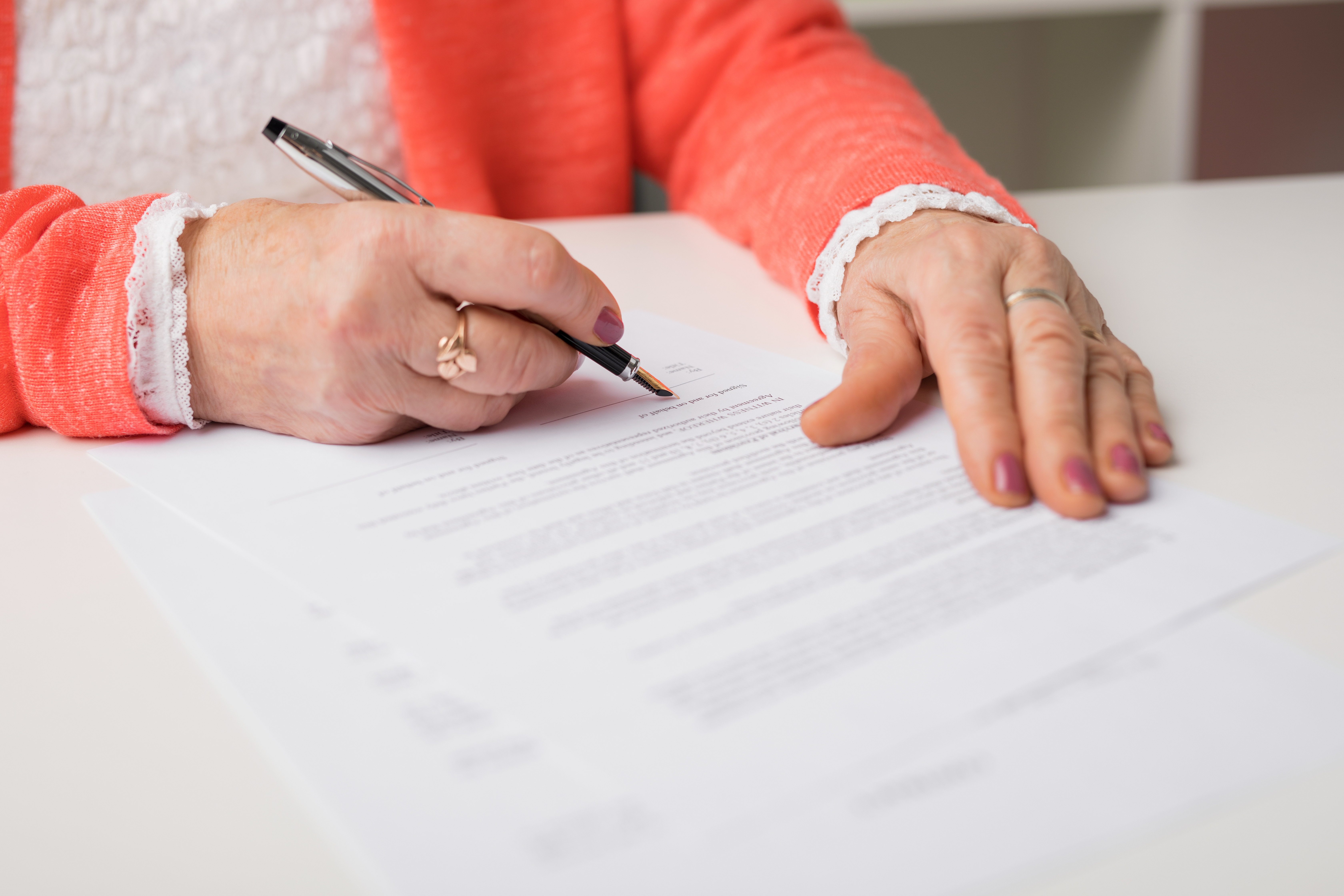 An older woman signing papers | Source: Shutterstock