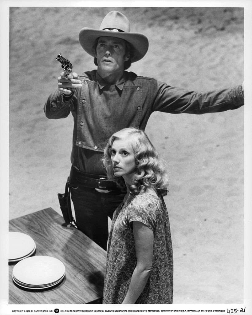 Clint Eastwood pointing a gun while Sandra Locke watches in a scene from the movie 'Bronco Billy', 1980 | Photo: Getty Images