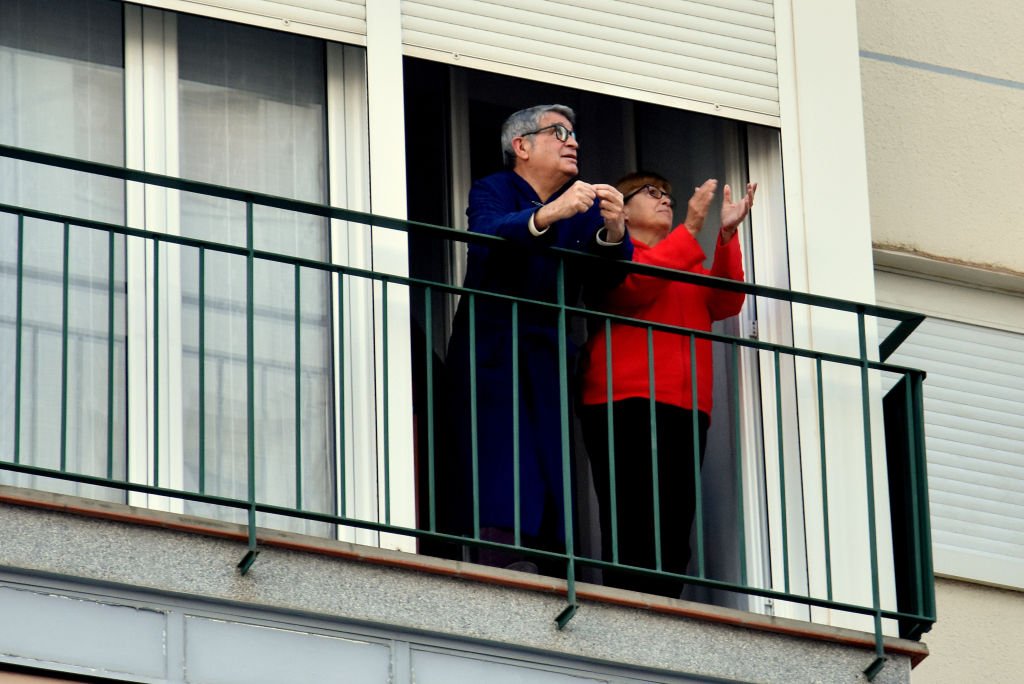 Pareja de ancianos desde la terraza de su casa para mostrar gratitud a los combatientes del covid-19. | Foto de Ramón Costa a través de Getty Images