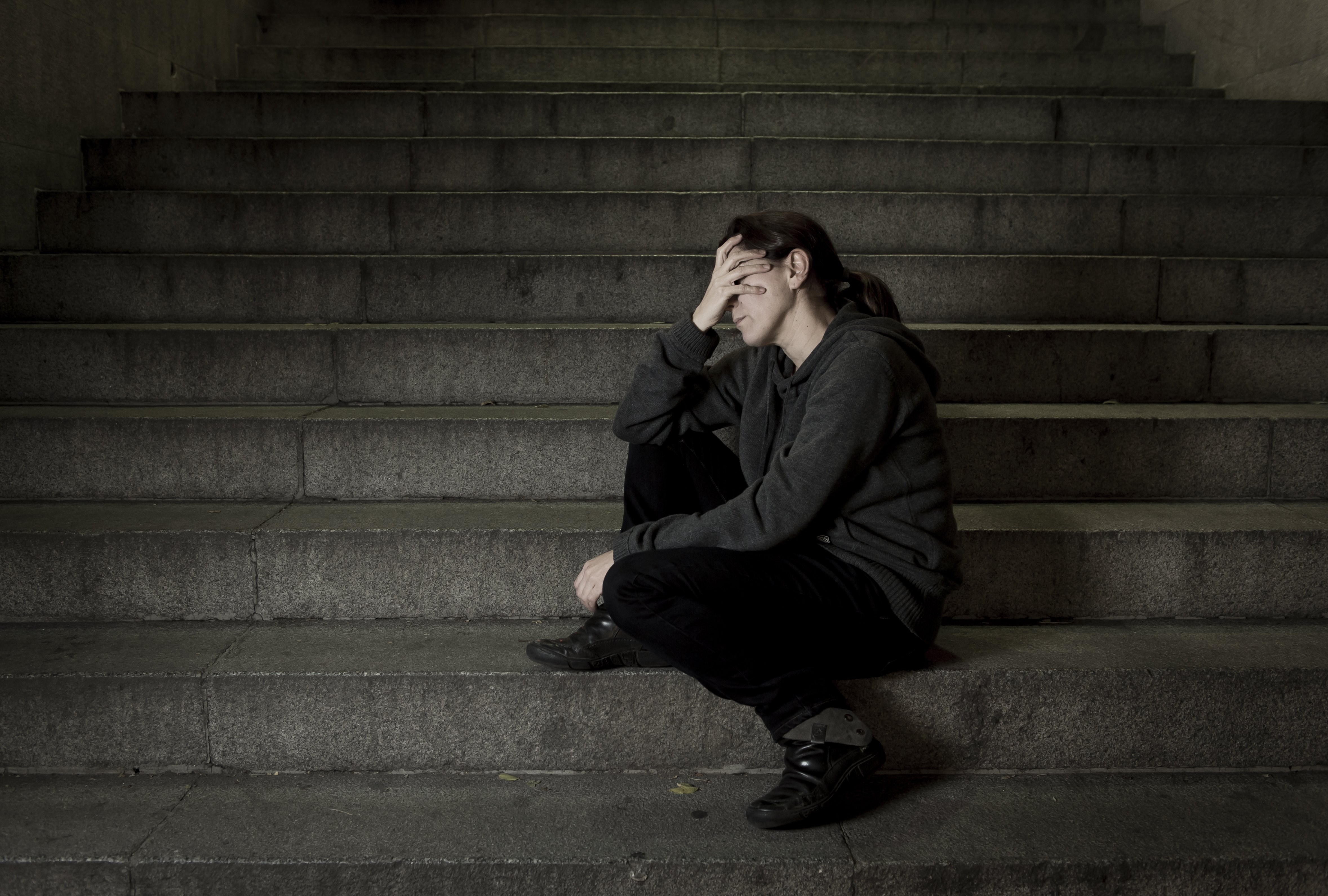 Sad woman alone on street staircase. | Photo: Shutterstock