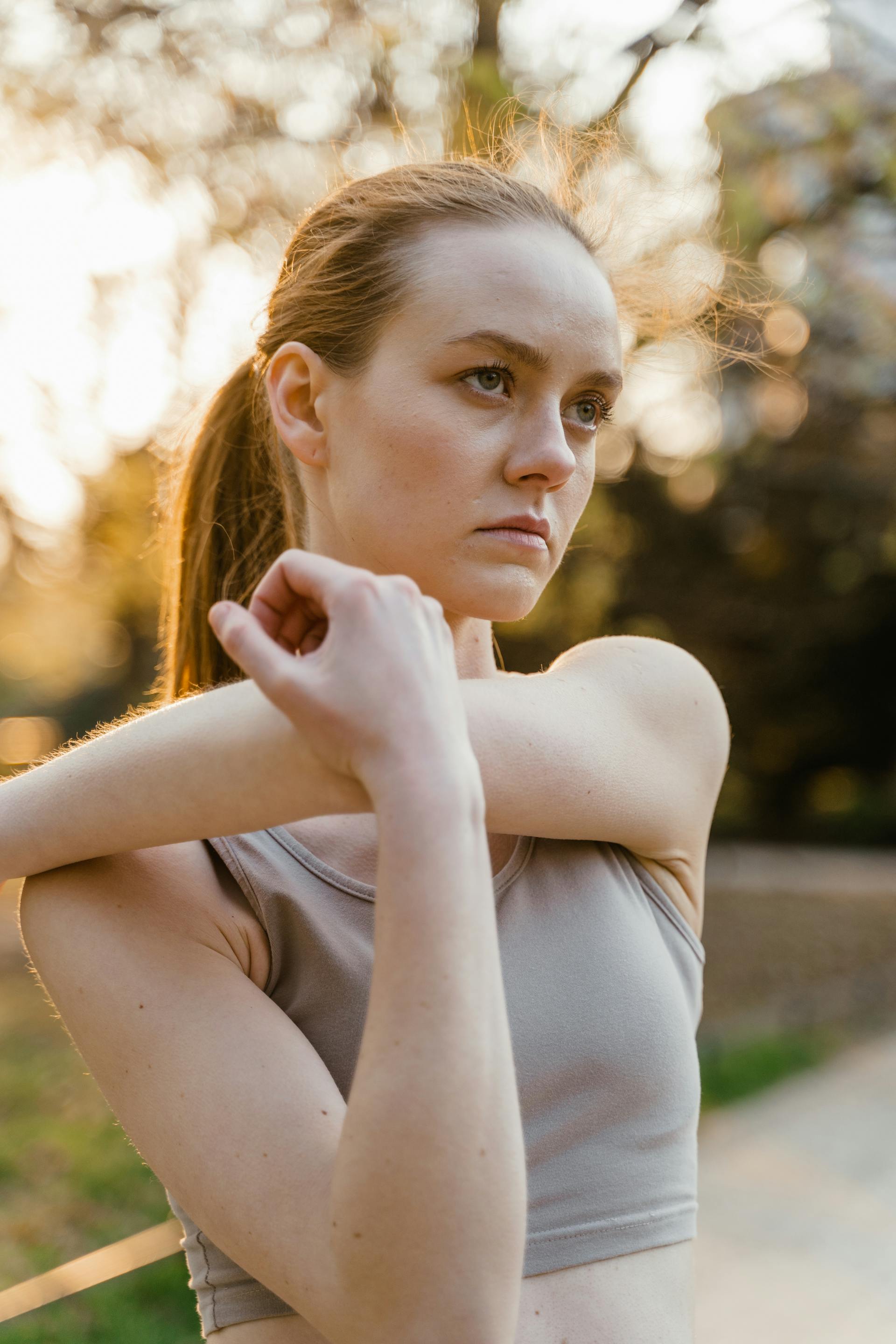 A woman with a serious facial expression stretching outdoors | Source: Pexels