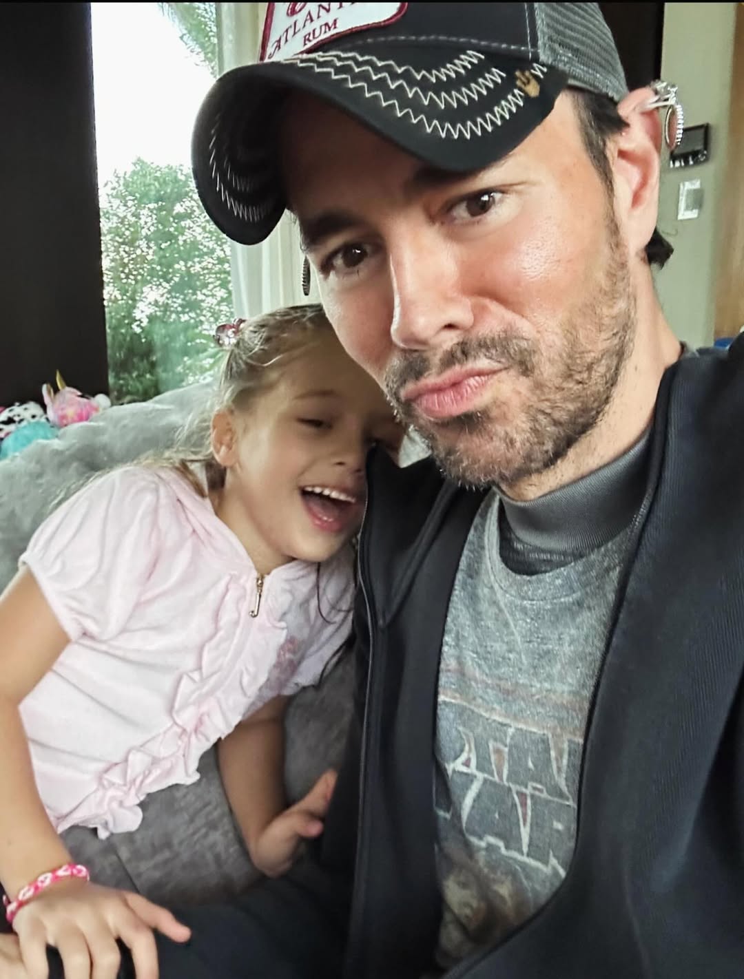 Enrique and Lucy Iglesias posing for a selfie on a couch, from a post celebrating Father's Day dated June 16, 2024 | Source: Instagram/annakournikova