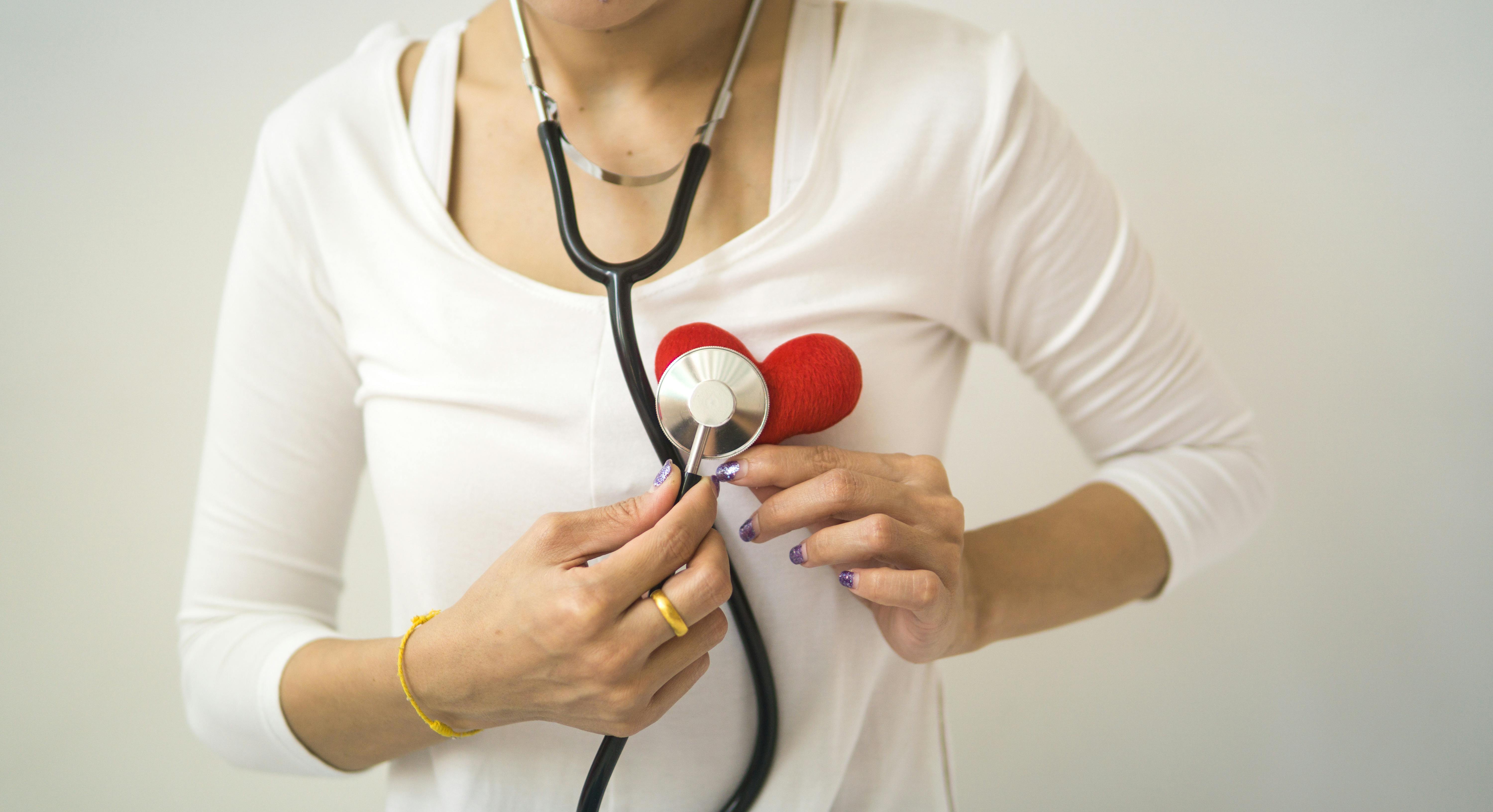 A woman holding a heart while listening to it with a stethoscope. | Source: Pexels