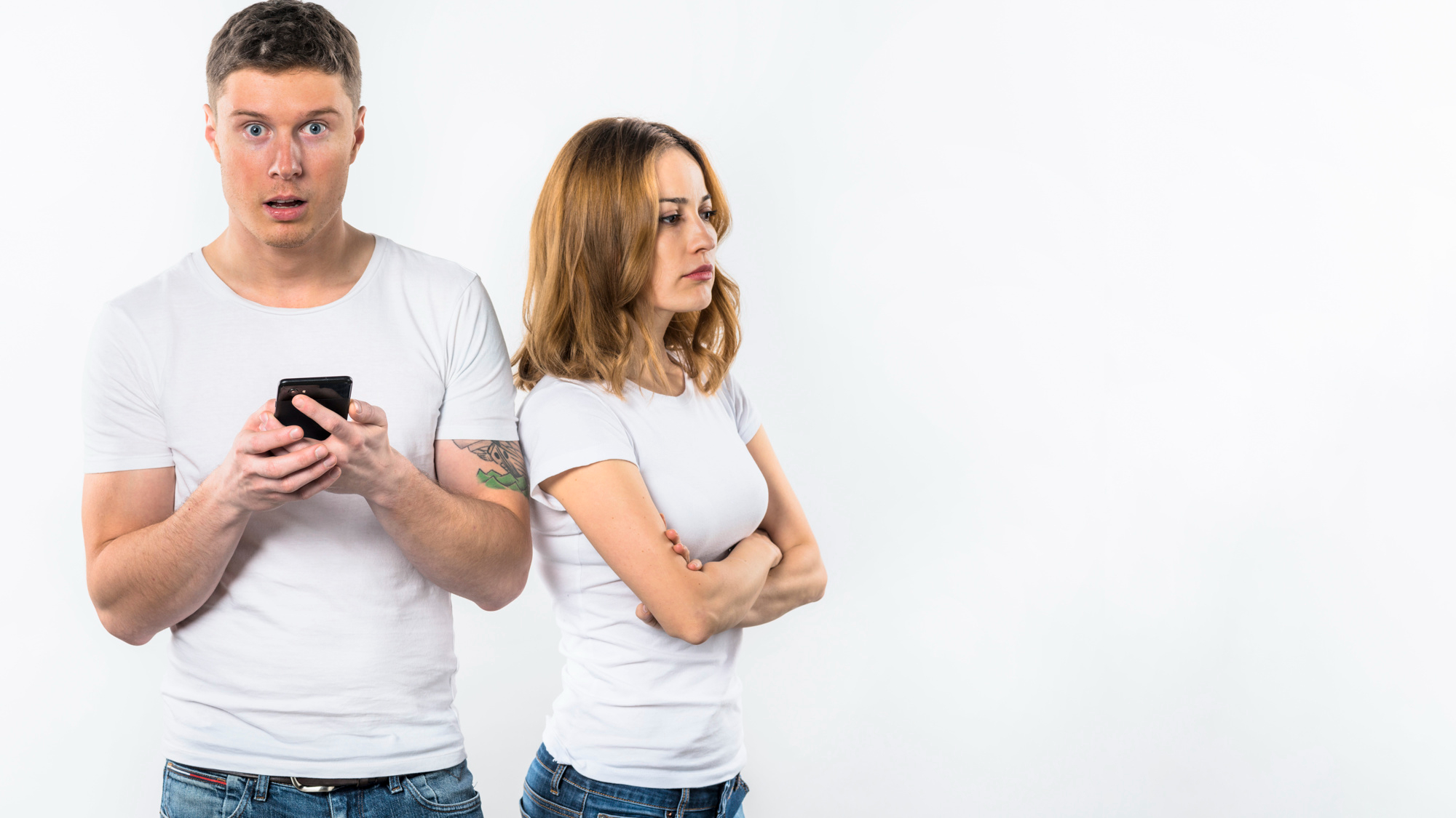 A man reacting shocked to something on a phone while his girlfriend looks upset | Source: Freepik