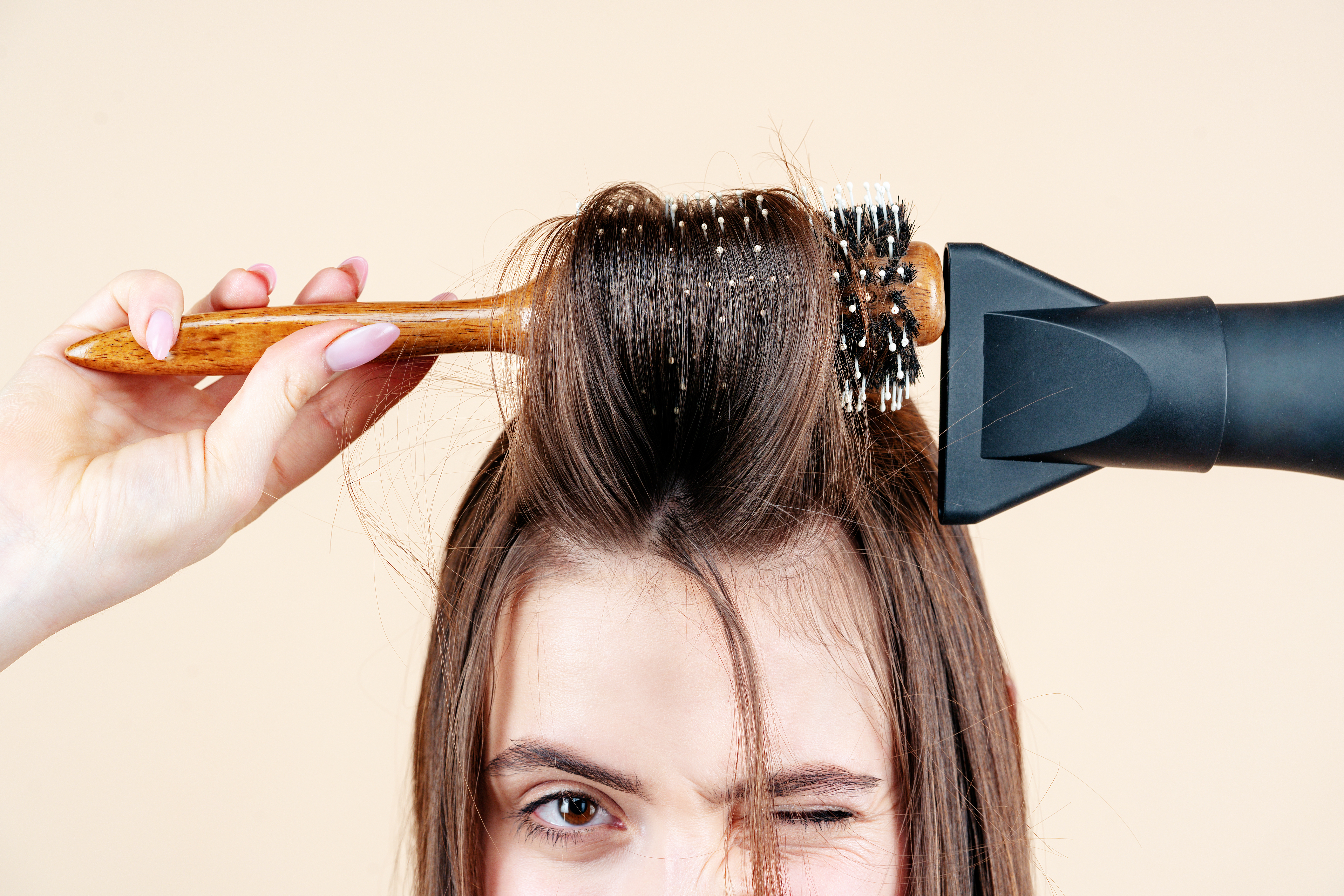 A close-up of a woman blow-drying her hair | Source: Shutterstock