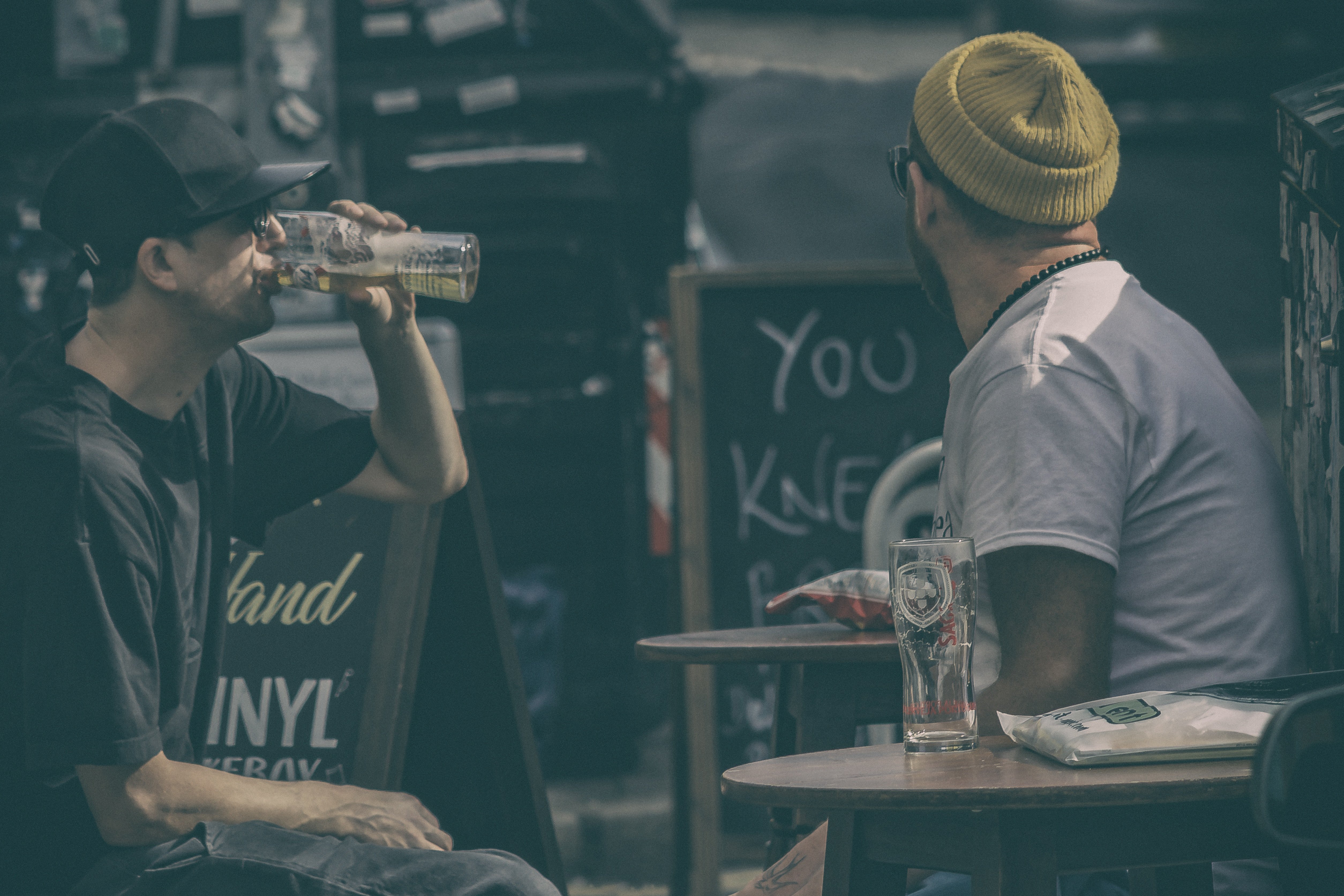 Two men sitting on a table drinking beer. | Source: Unsplash