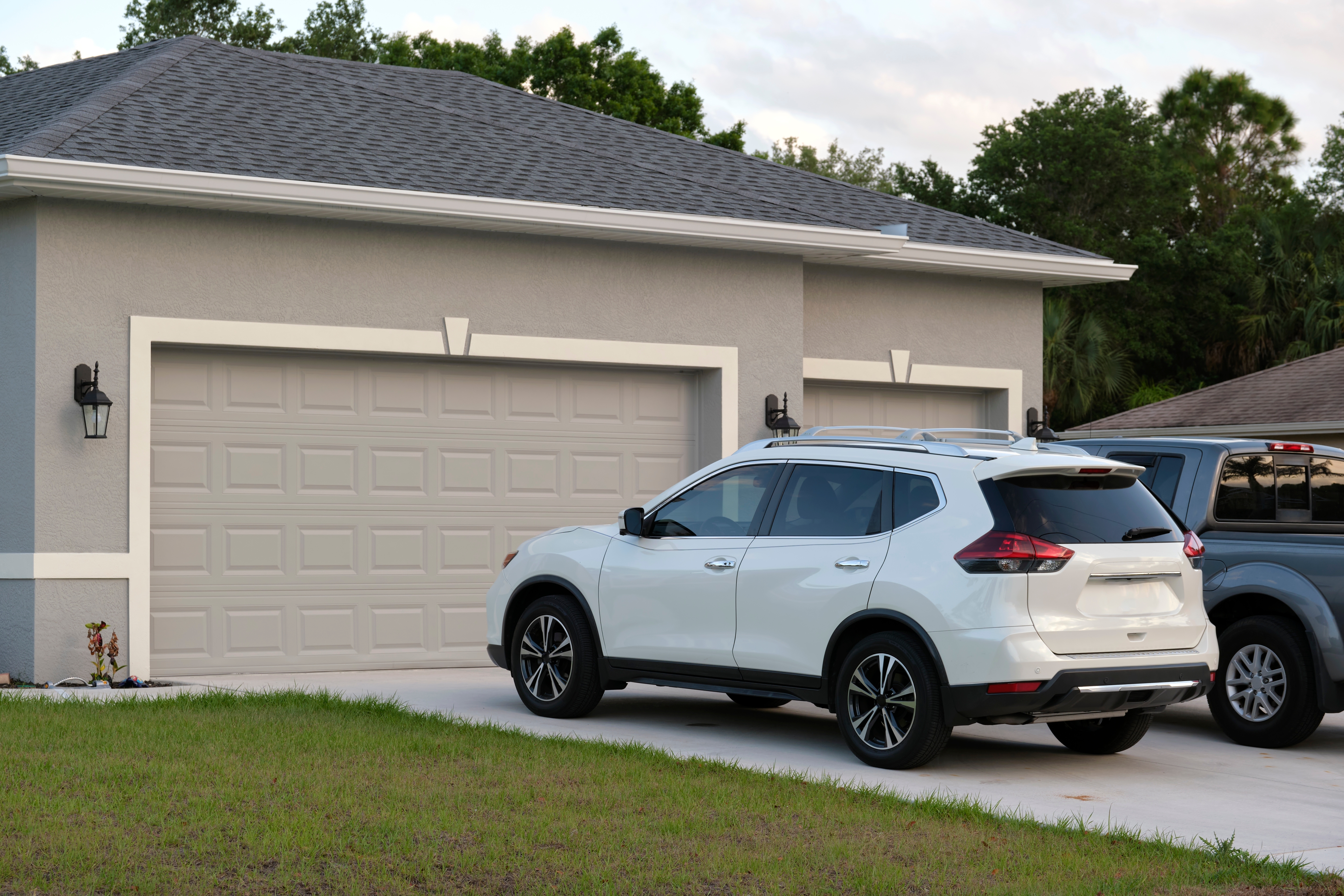 Car parked in front of wide garage double door on concrete driveway of new modern american house. | Source: Shutterstock