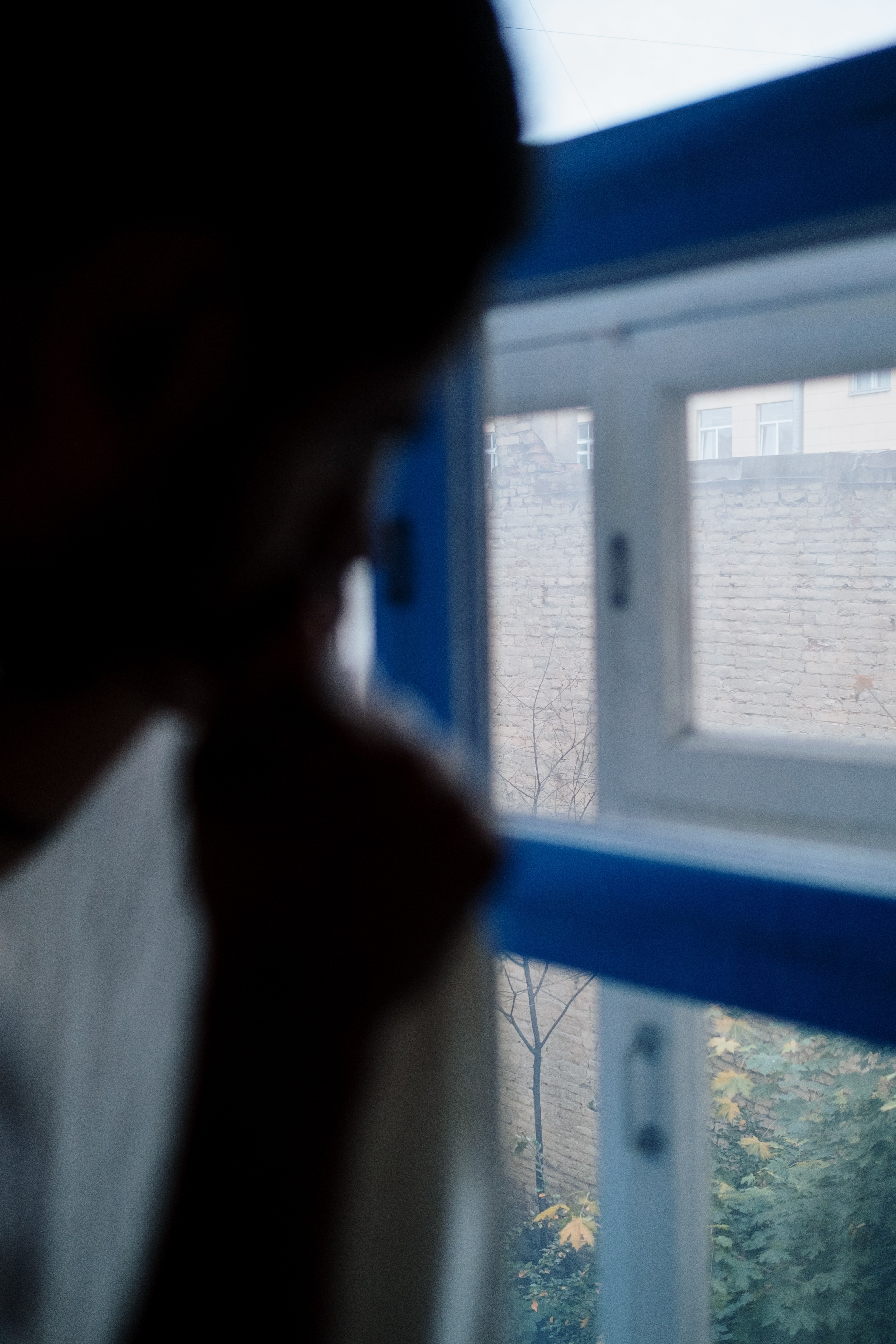 A man pulls back the curtains to peep through a window. | Photo: Pexels. 