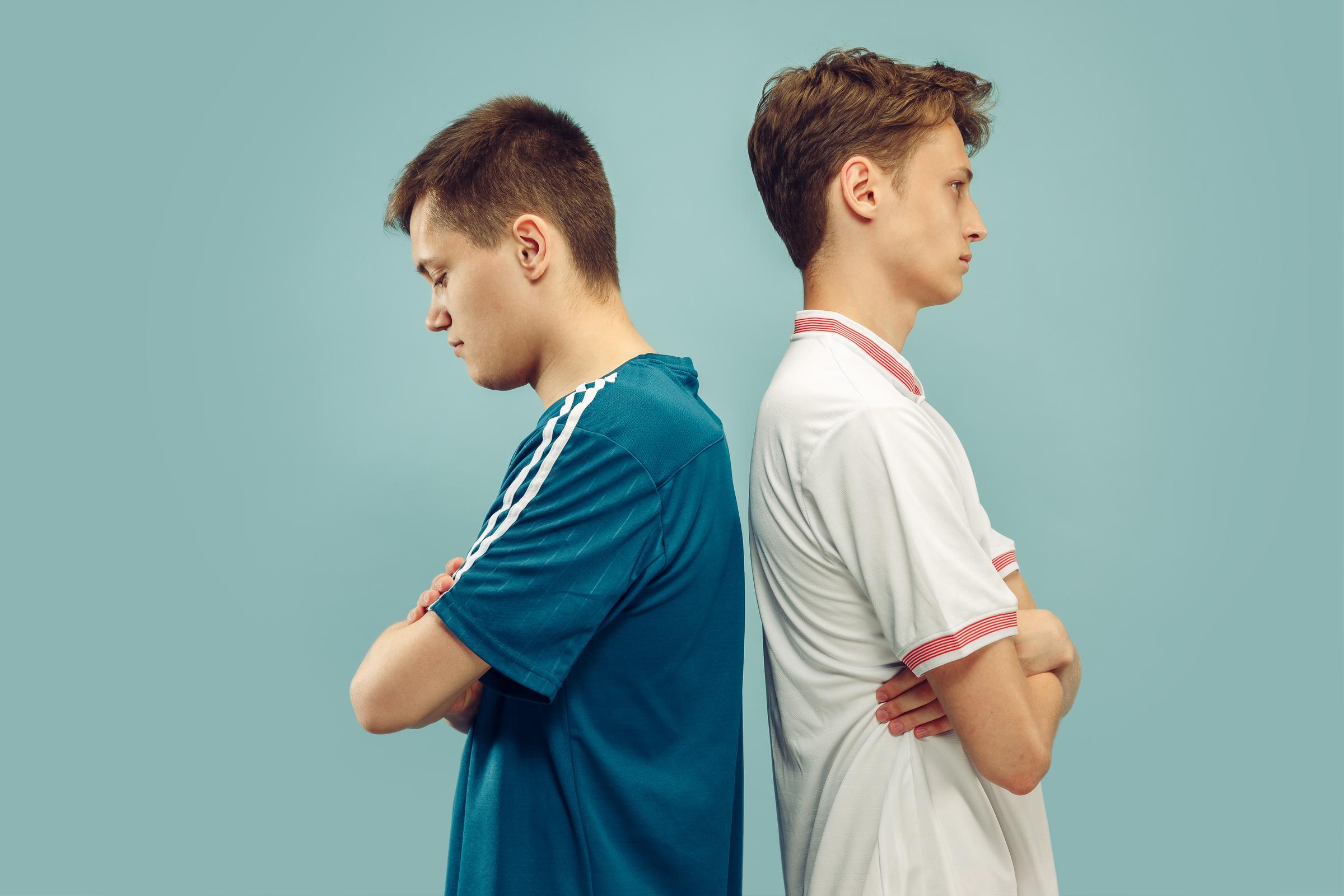 Two young men standing with their backs facing each other | Source: Freepik