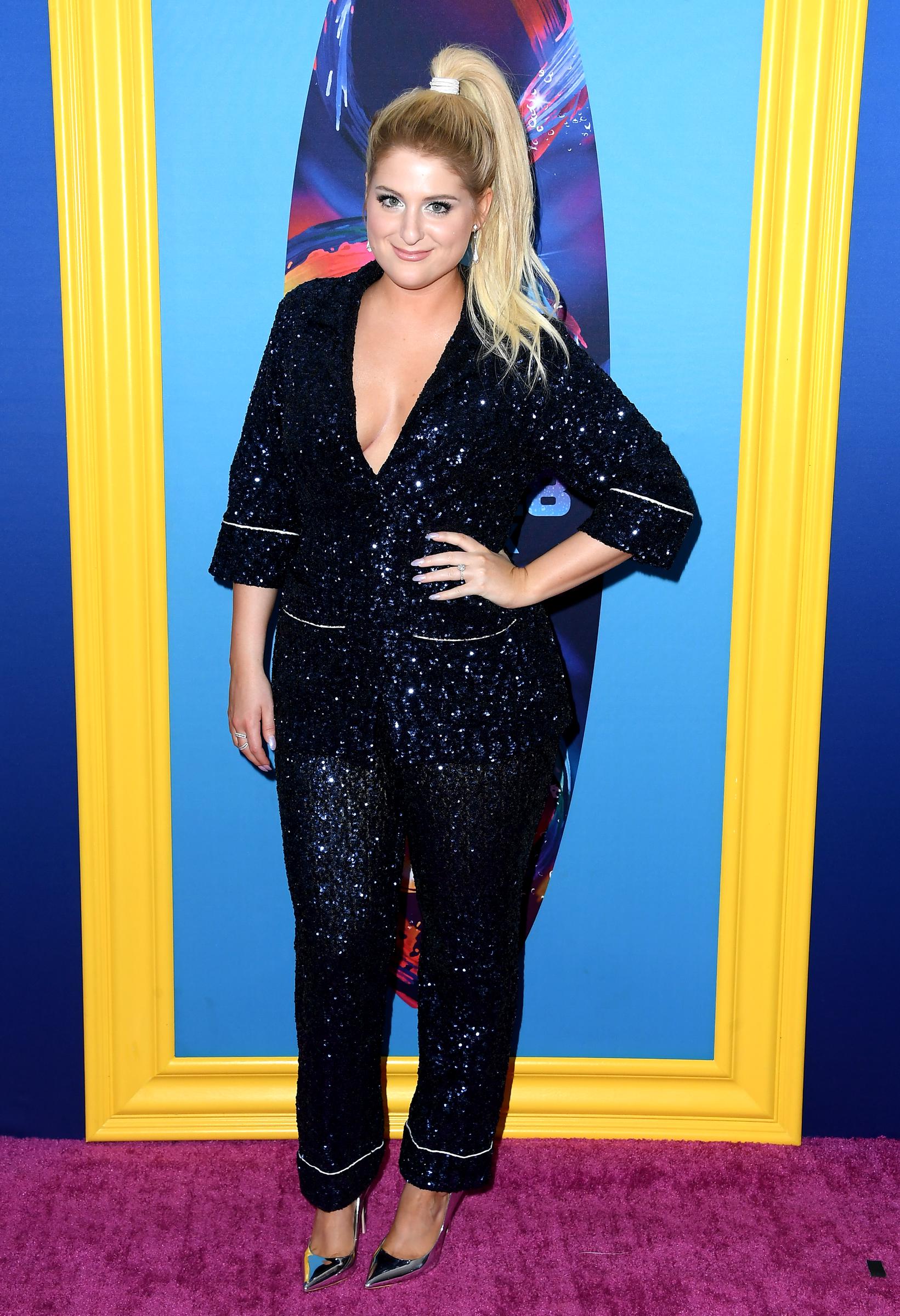 Meghan Trainor sparkles on the carpet at FOX's Teen Choice Awards in Inglewood, dazzling in a navy sequined suit with a plunging neckline. With her hair pulled into a sleek high ponytail and metallic heels, she exudes bold confidence and modern glam.