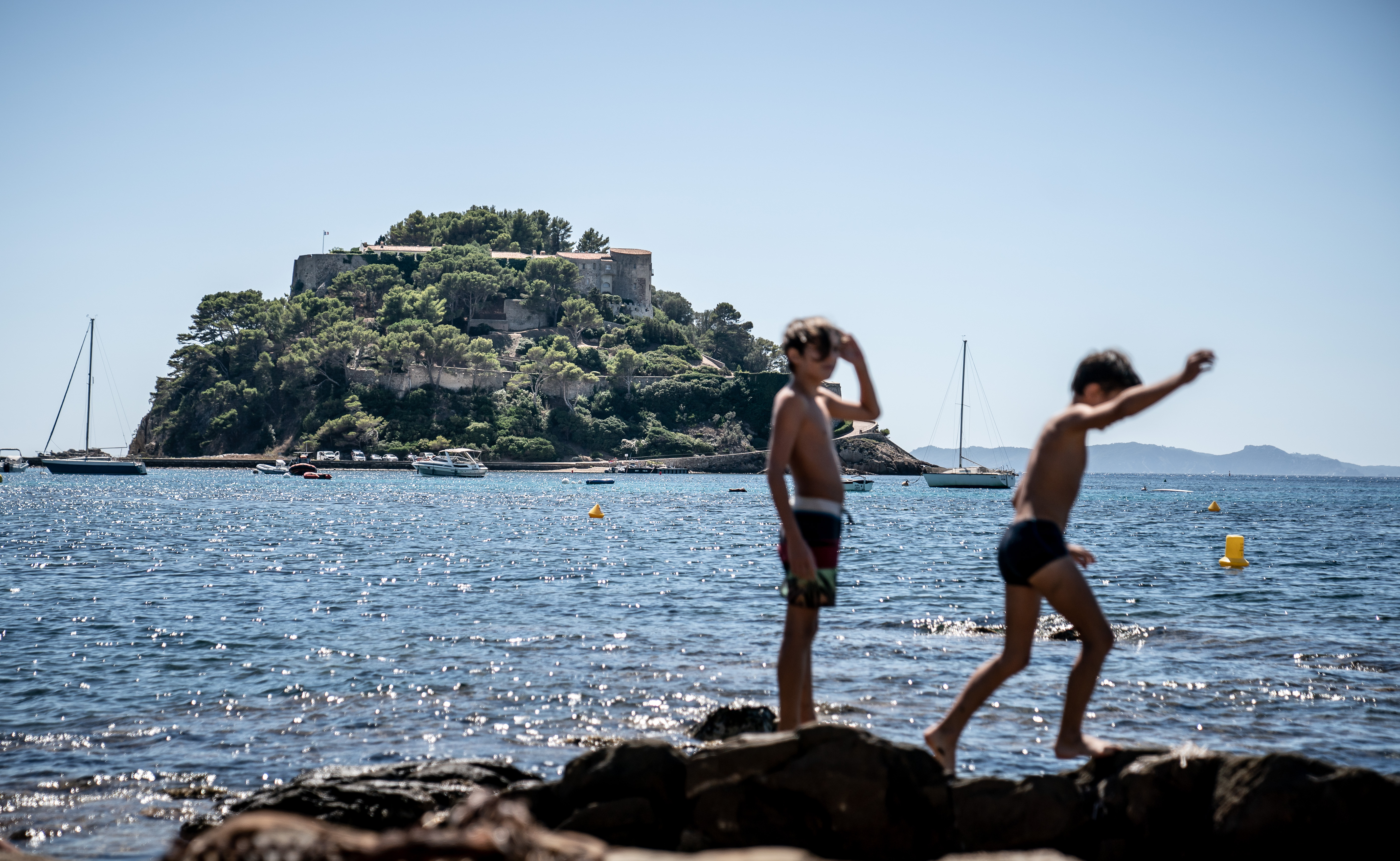 Children jump over the rocks in front of the Fort de Bregancon on August 20, 2020 | Source: Getty Images