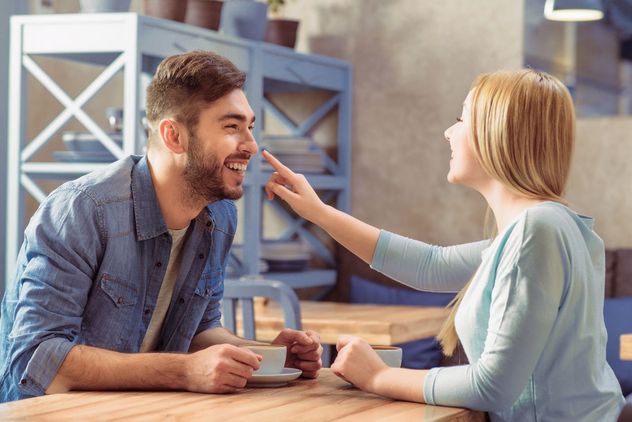 A man and a woman look happy over coffee. | Source: Shutterstock