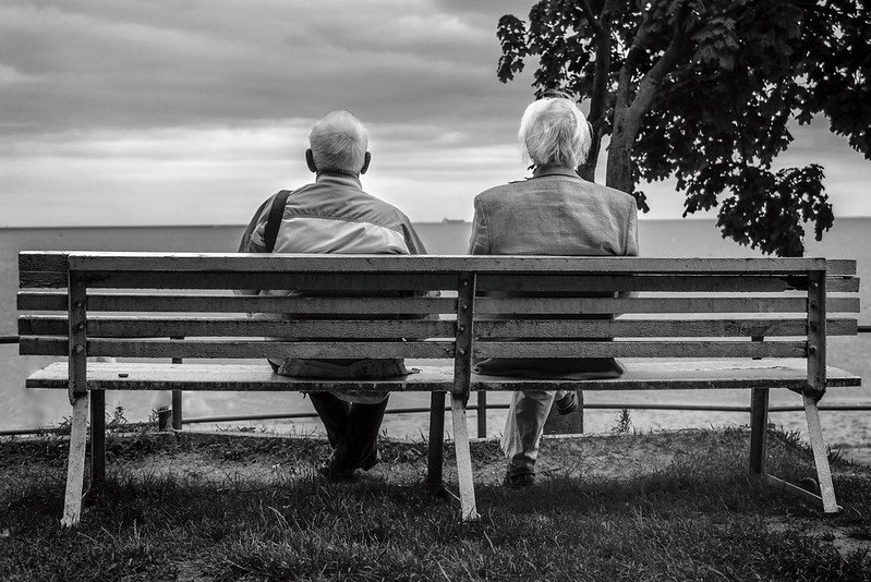 Two old men sitting together on a park bench. | Photo: Flickr