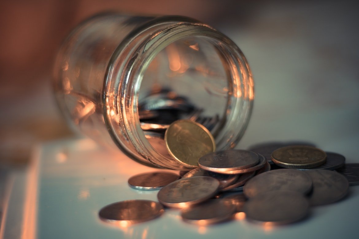 Un envase de vidrio lleno de monedas. | Foto: Unsplash
