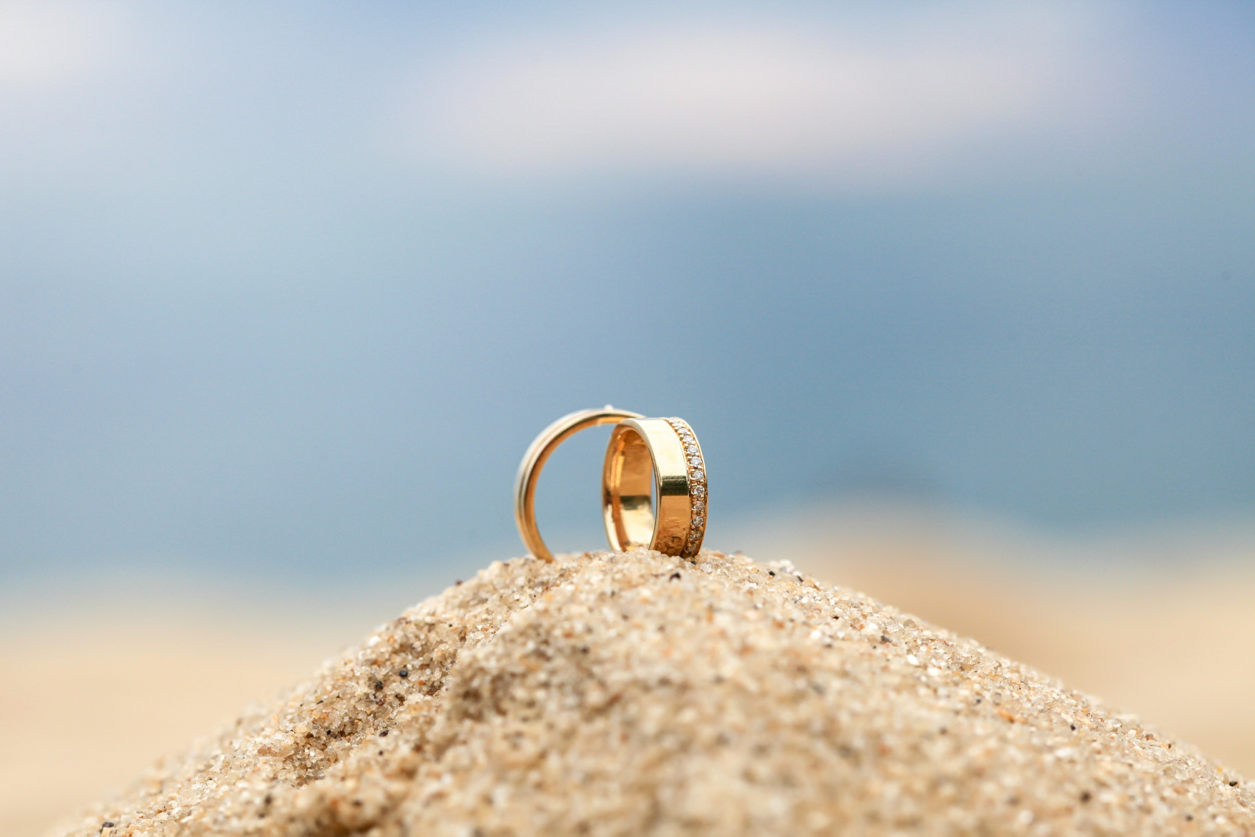 Three rings lie in a heap of sand on a beach | Photo: Pexels/Marcio Norris