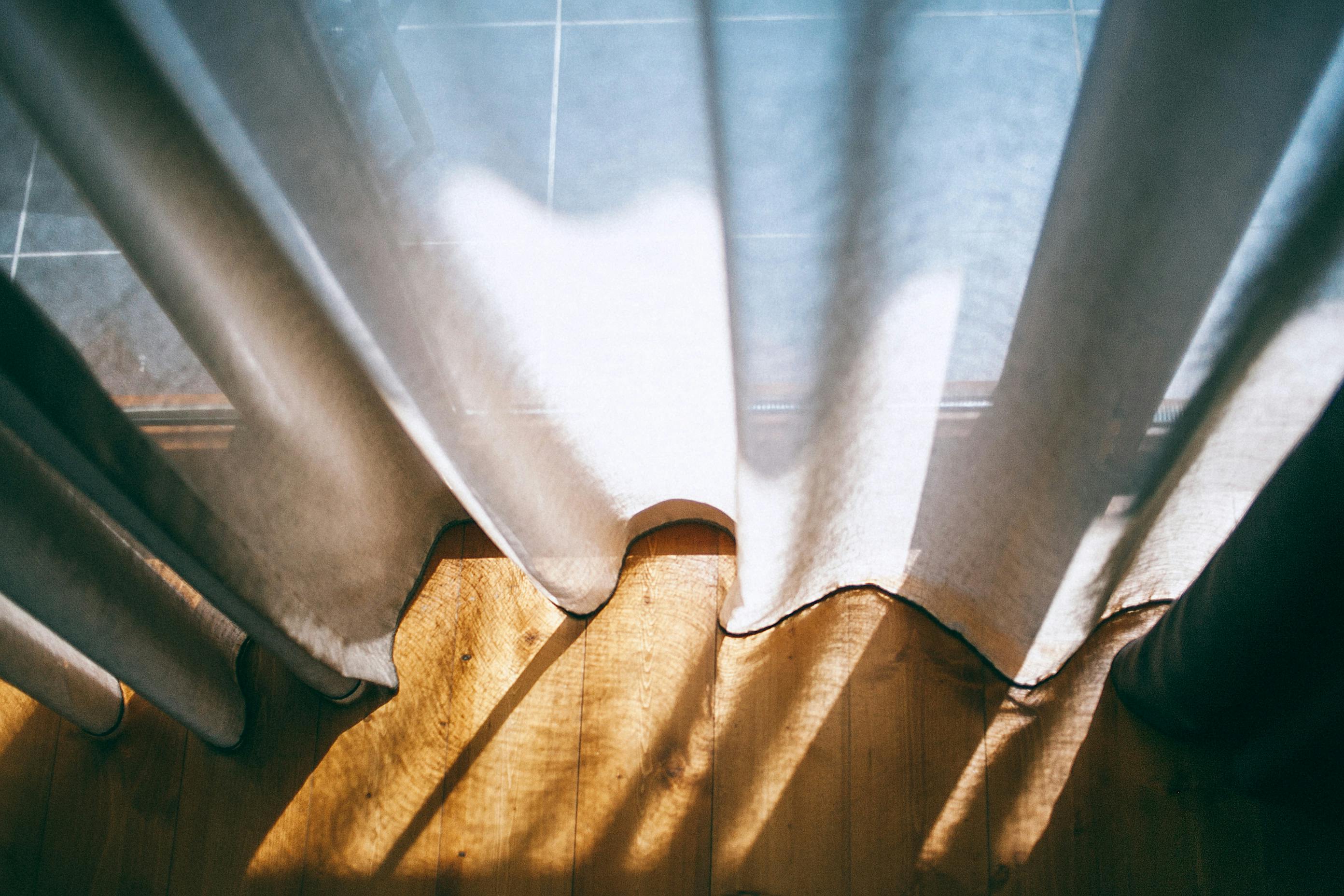 Curtains hanging by a window highlight how fabric surfaces trap dust and affect indoor air quality. | Source: Pexels