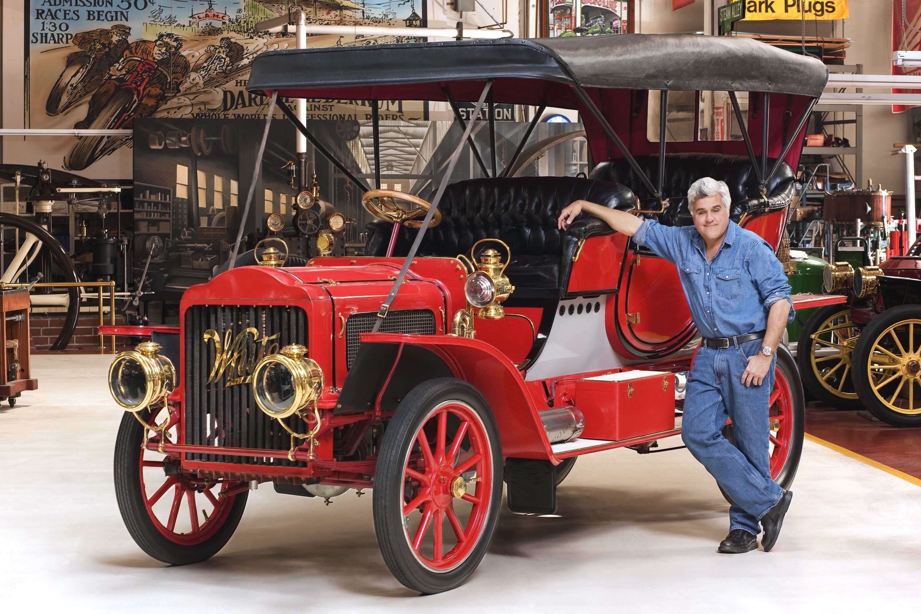 Jay Leno smiles as he stands next to his 1908 White Steam Car in his garage. | Source: Getty Images