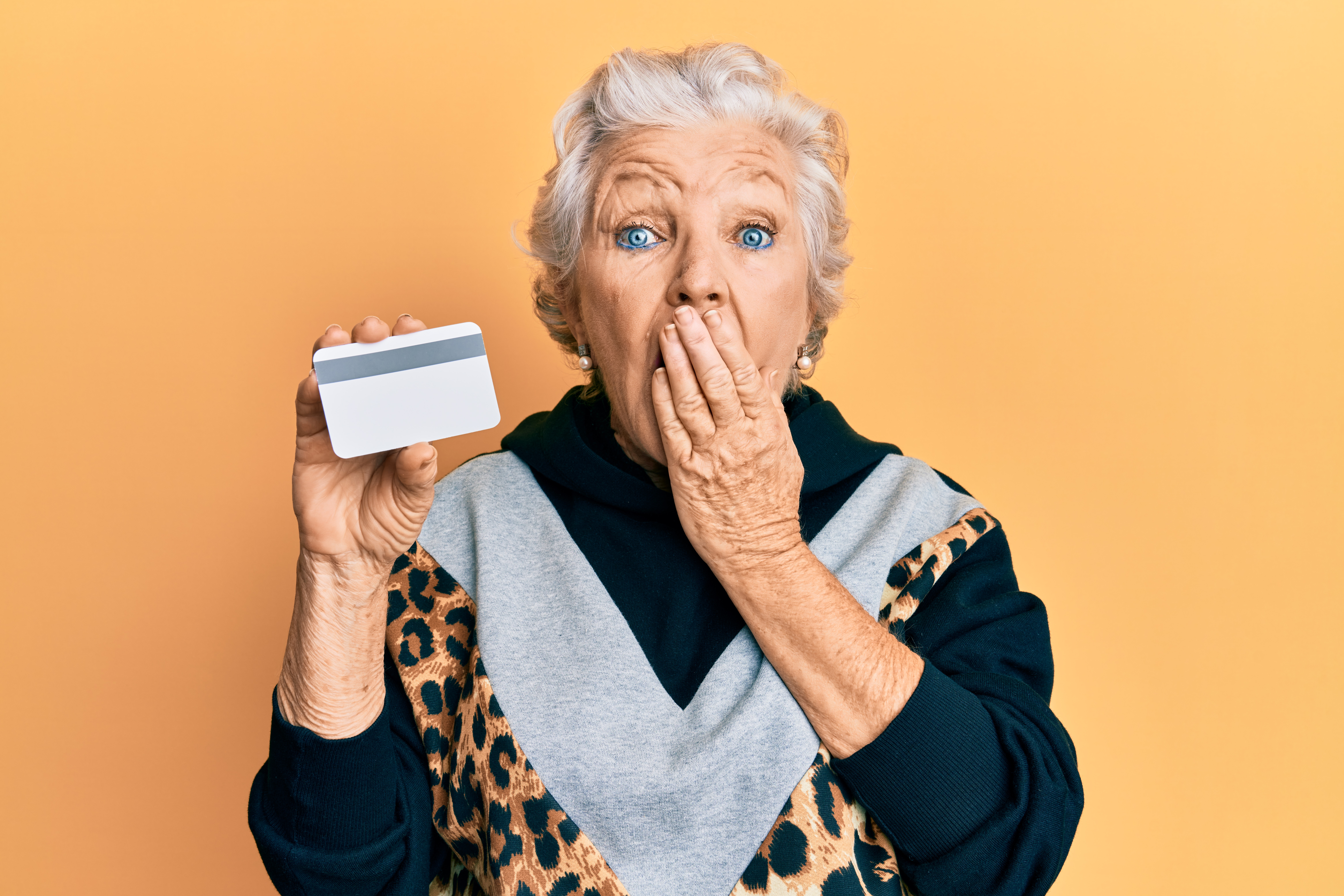 An elderly woman holding a credit card | Source: Shutterstock