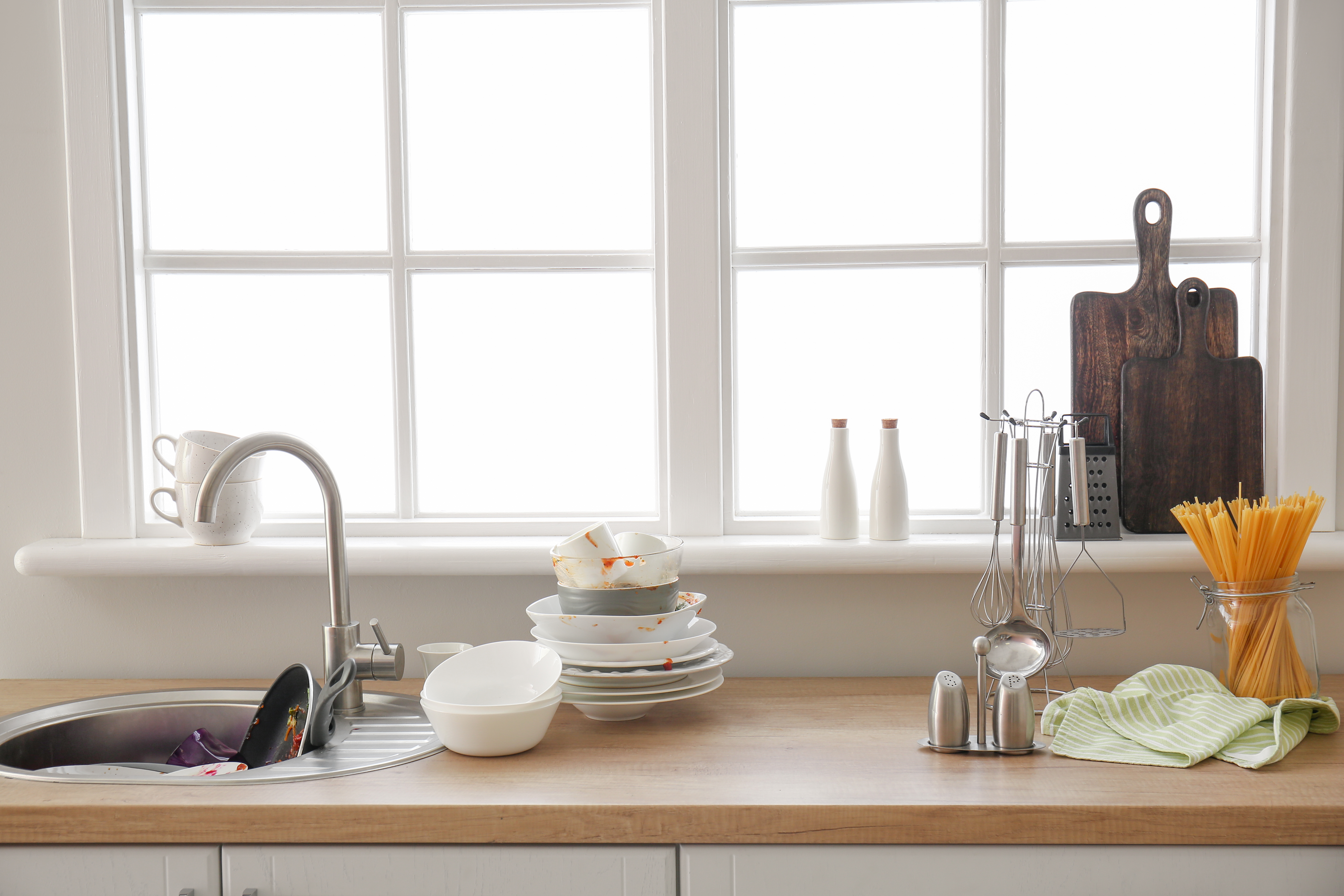 Dirty dishes piled up next to a kitchen sink | Source: Shutterstock