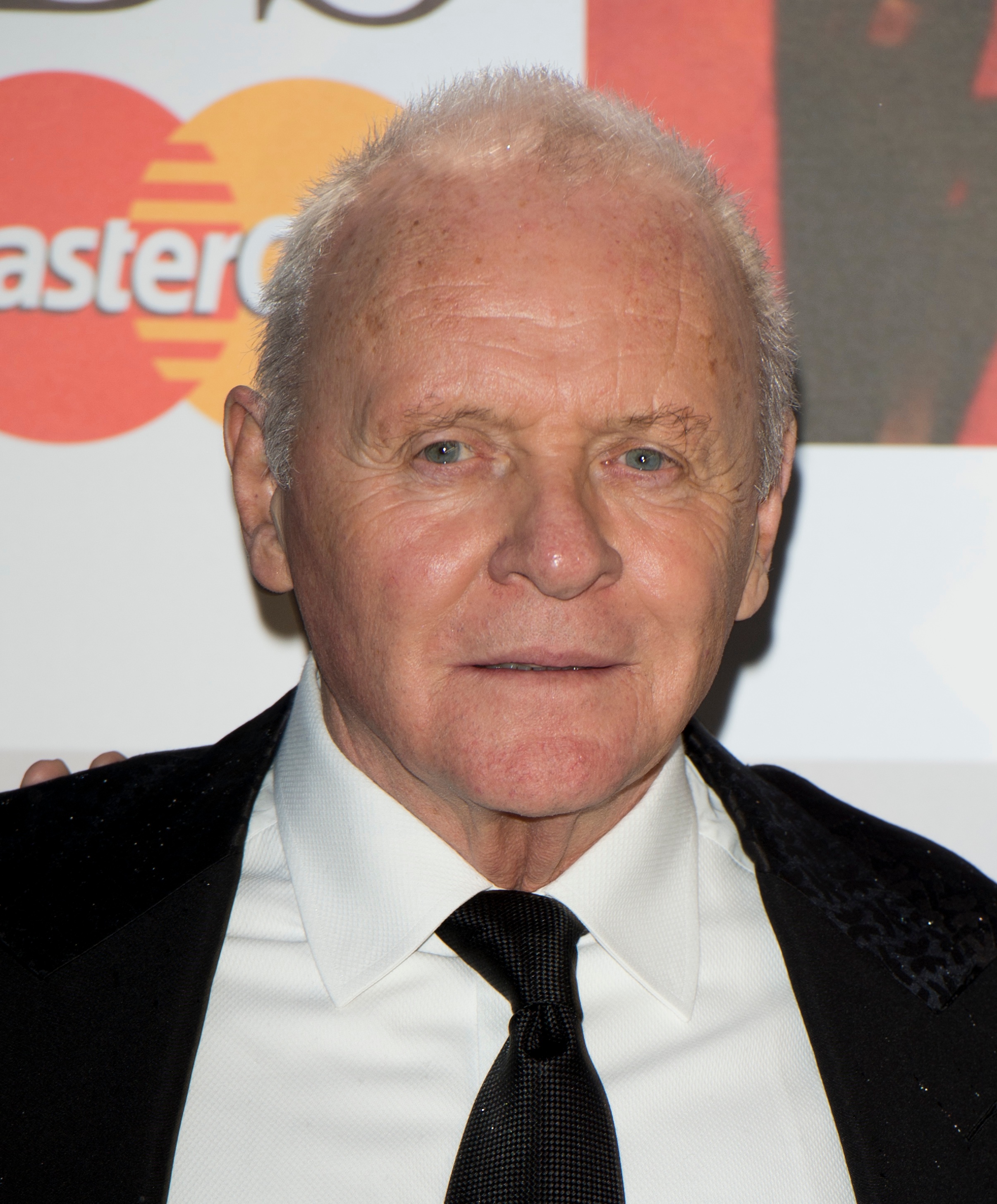 Anthony Hopkins attends the Classic Brit Awards, exuding timeless elegance and quiet confidence. Clad in a crisp white shirt, black tie, and velvet-trimmed jacket, he radiates understated finesse. His composed expression reflects both his artistic depth and enduring presence in the world of performance.