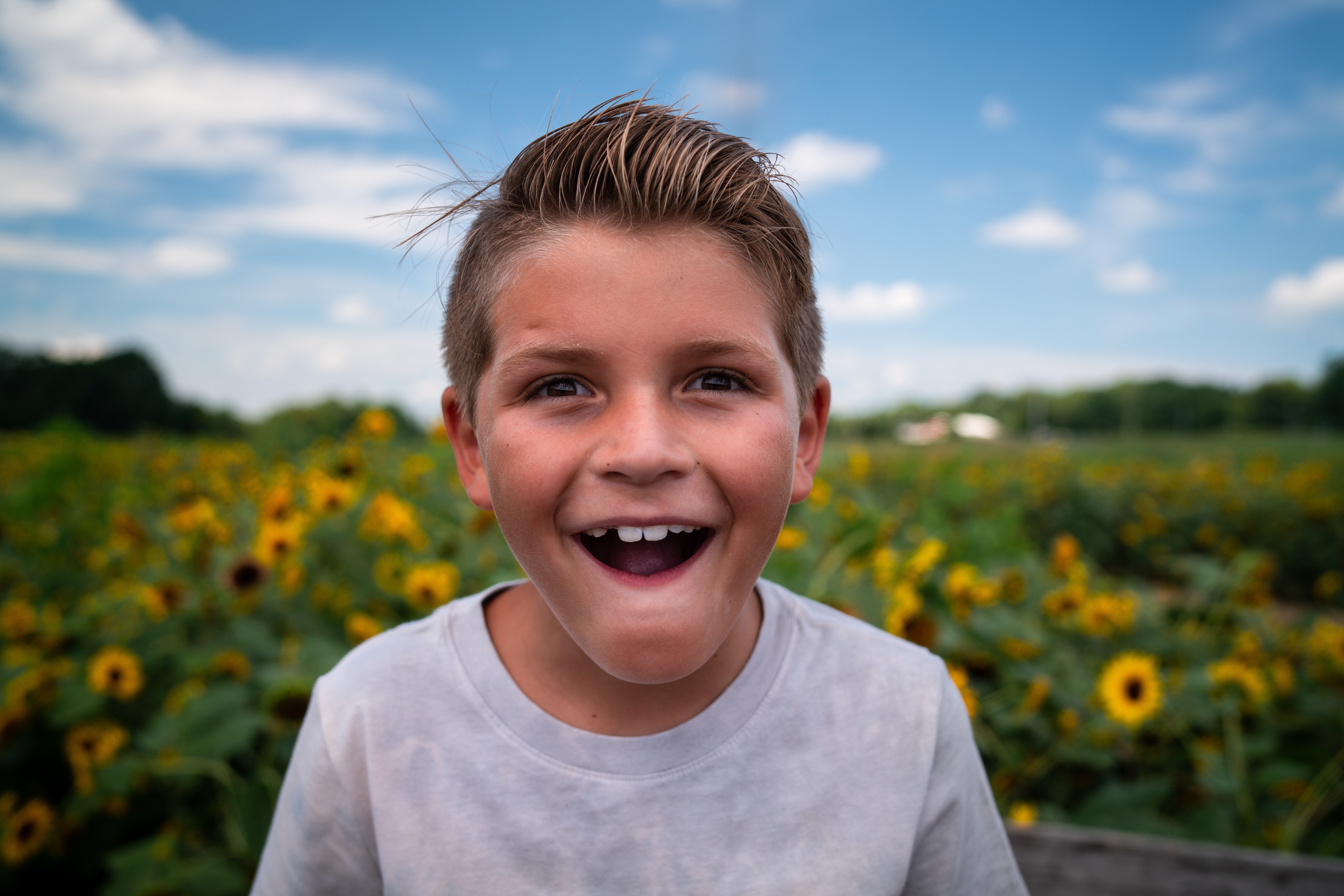Smiling boy wearing a gray T-shirt outdoors | Source: Unsplash