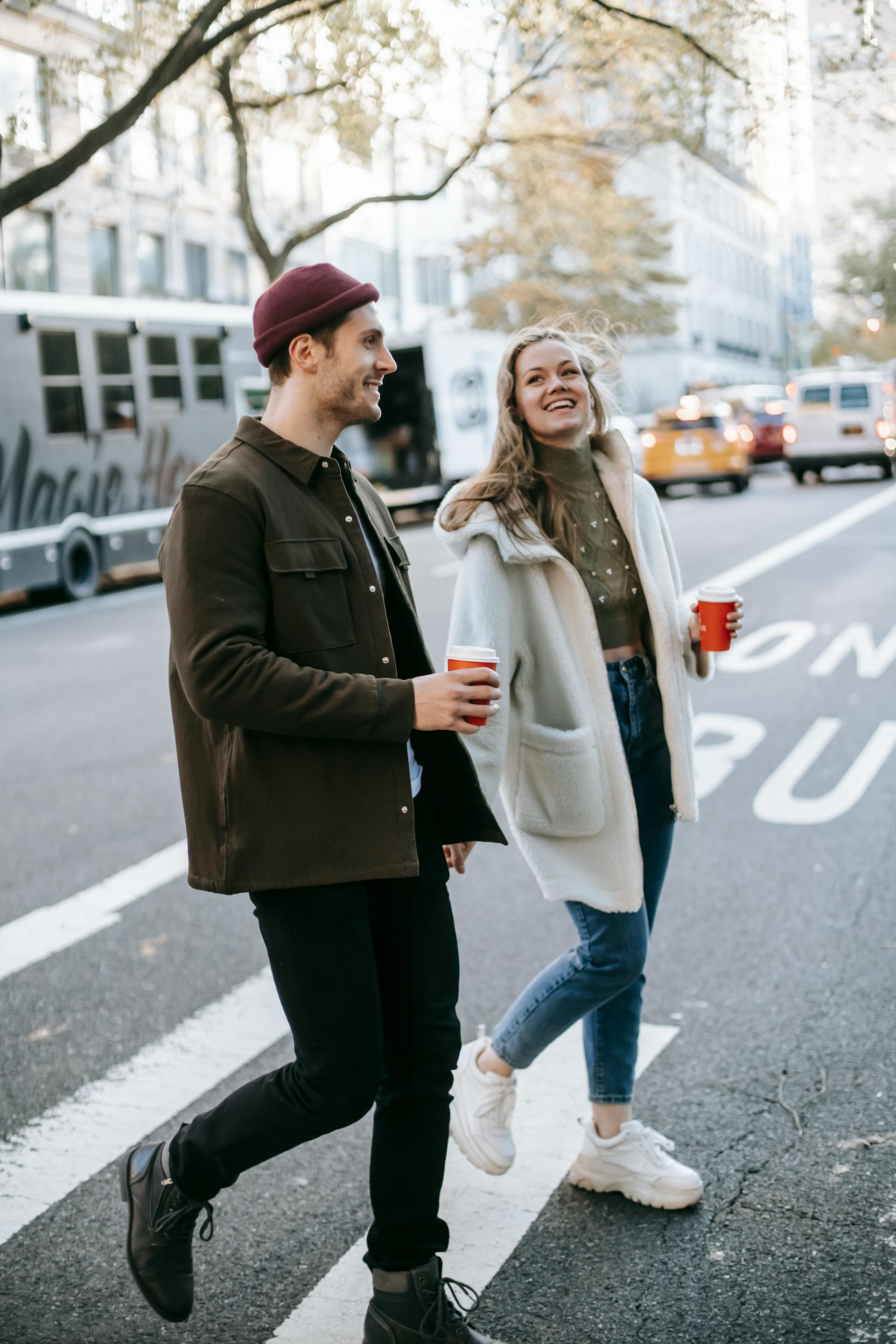 A couple walking on the street with coffee cups | Source: Pexels