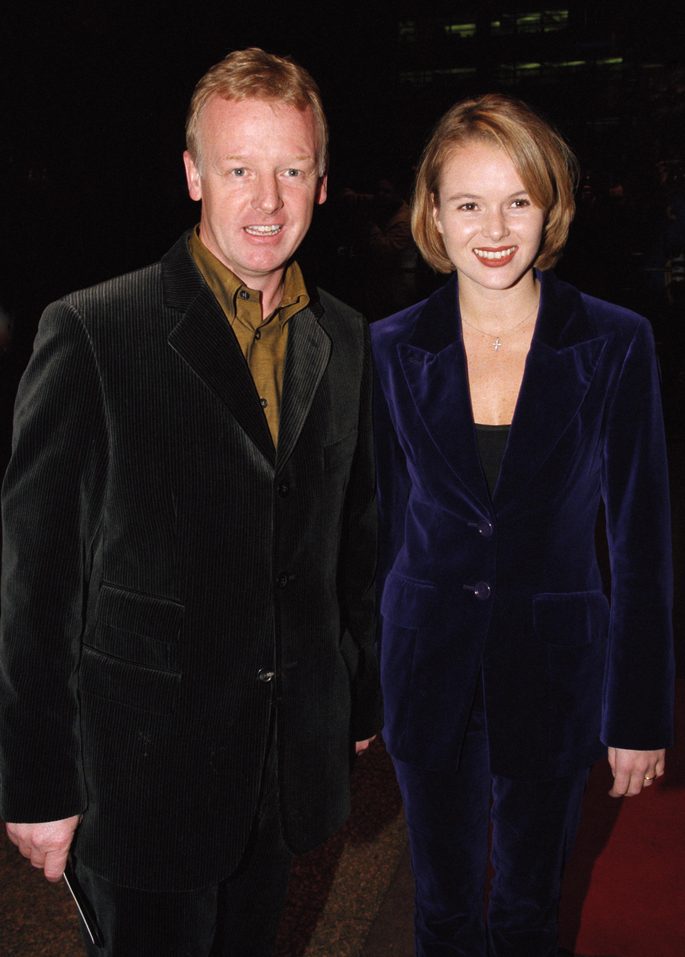 Dennis and Holden arrive hand in hand at the London premiere of "Shooting Fish". Dennis wore a dark corduroy blazer over an olive shirt, while Holden opted for a deep navy velvet suit paired with a cross necklace and a bold red lip.