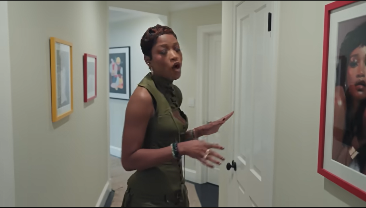 Blame it on Mom! Palmer gestures toward her hallway art collection, laughingly reminding viewers that Sharon Palmer is the one responsible for all these portraits. | Source: YouTube/@Archdigest