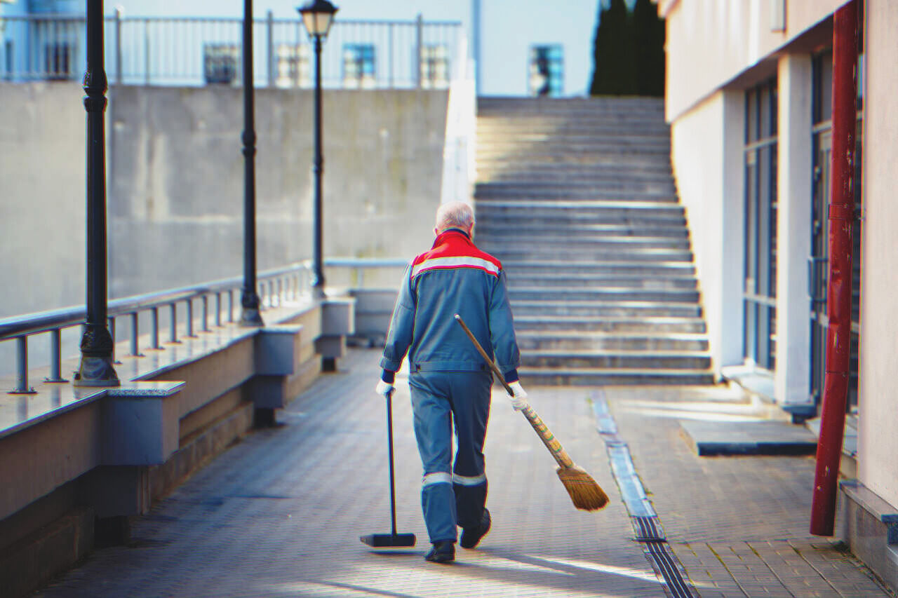 A janitor walking with cleaning essentials | Source: Shutterstock