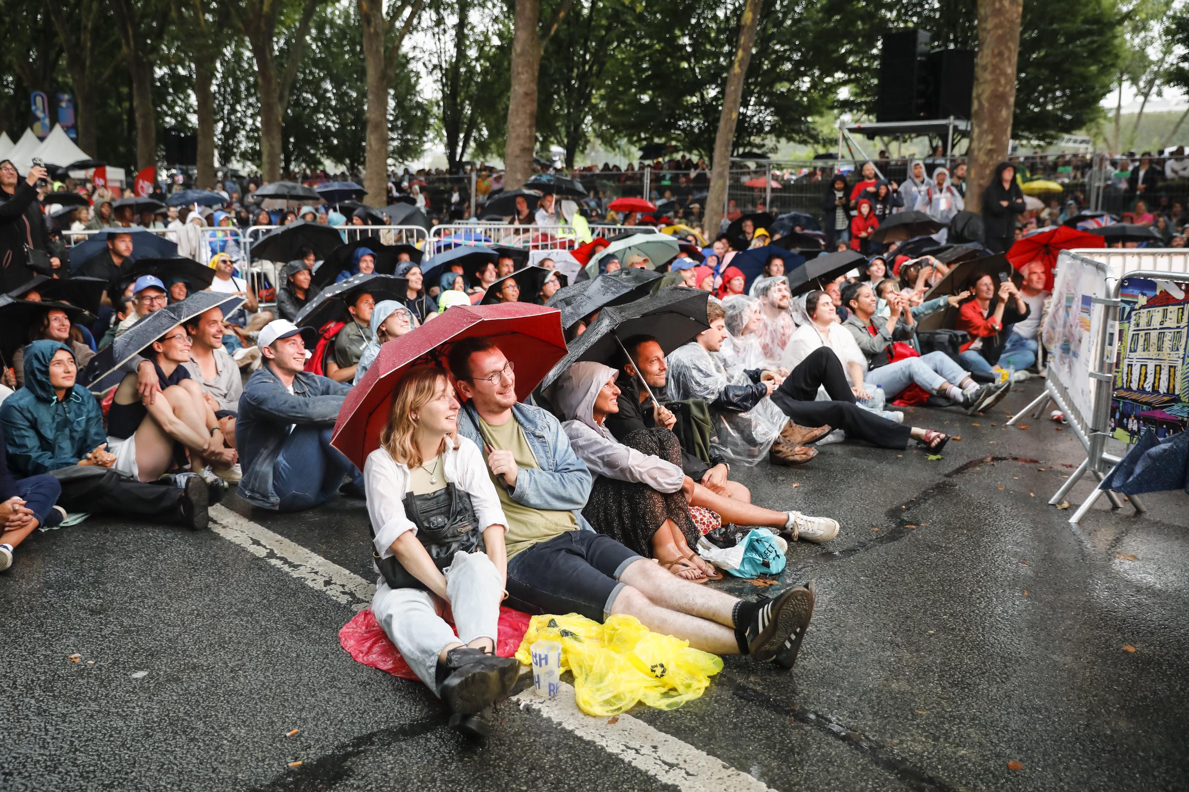 Parisians and tourists watch the opening ceremony of the Olympic Games on a quay of the Seine River in the rain in Paris, France, on July 26, 2024. | Source: Getty Images