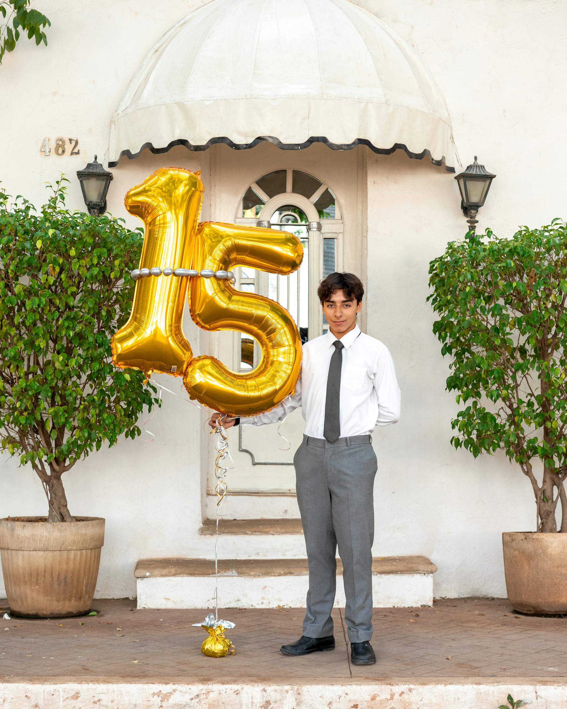 A boy standing with birthday balloons | Source: Pexels