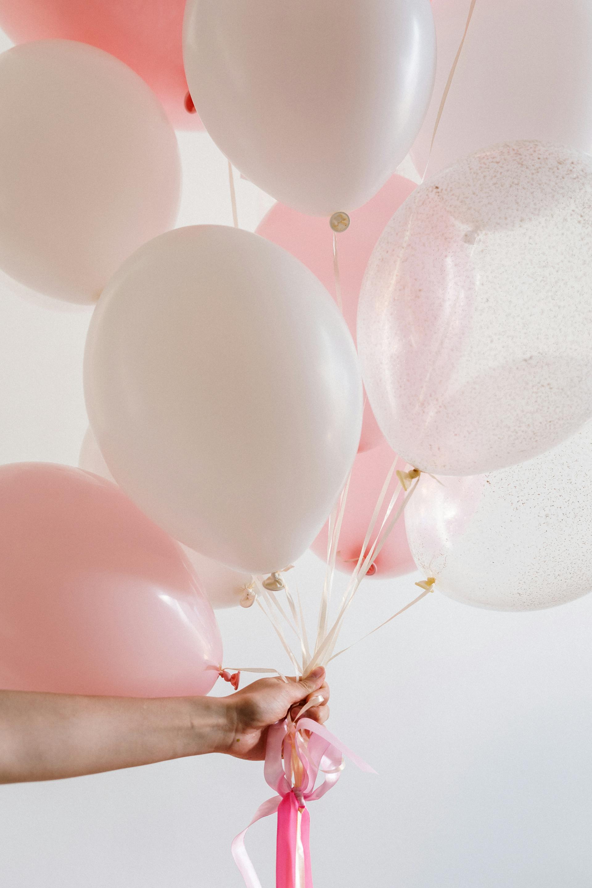 A person holding pink and white balloons | Source: Pexels
