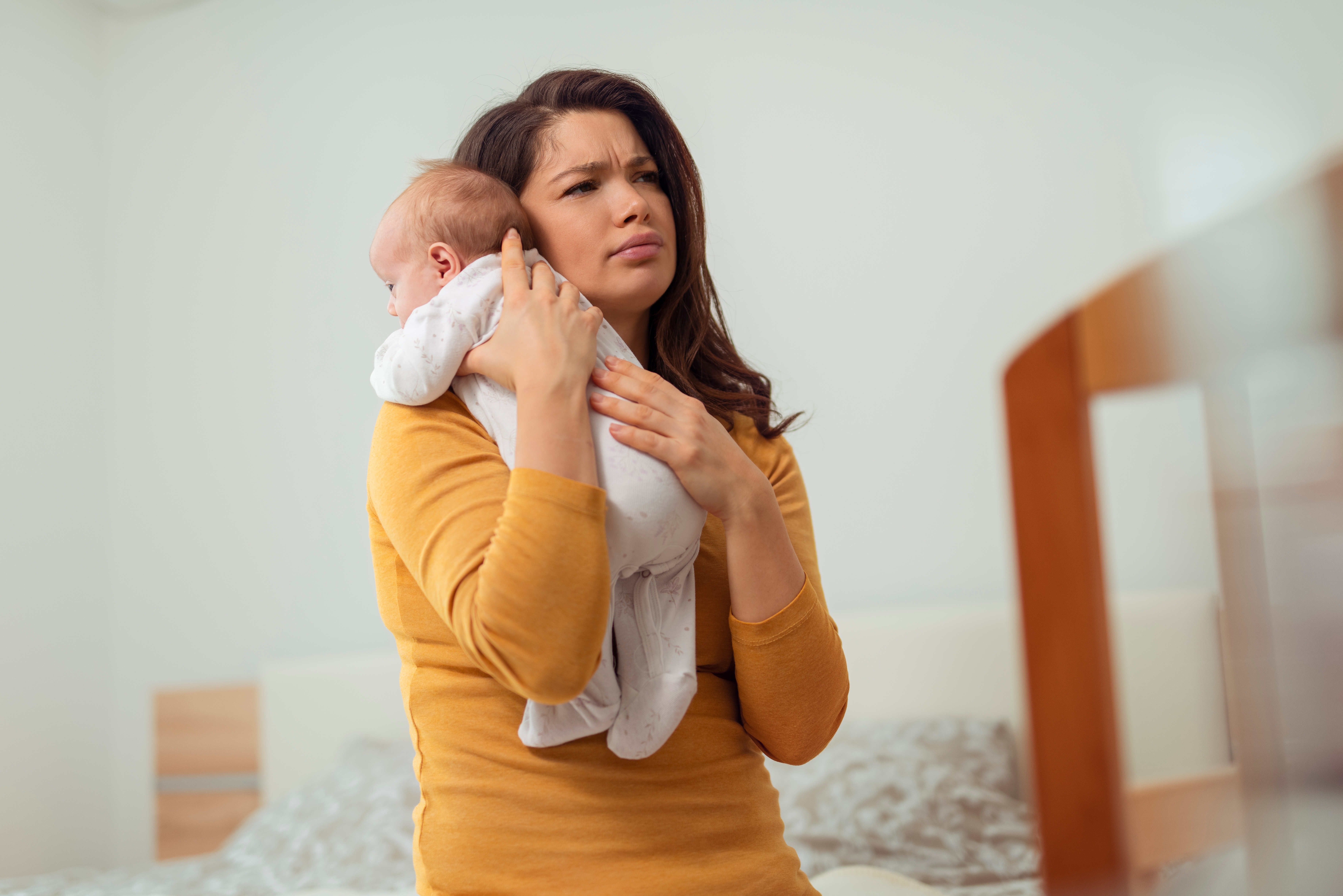A woman looking tired while holding a baby | Source: Shutterstock