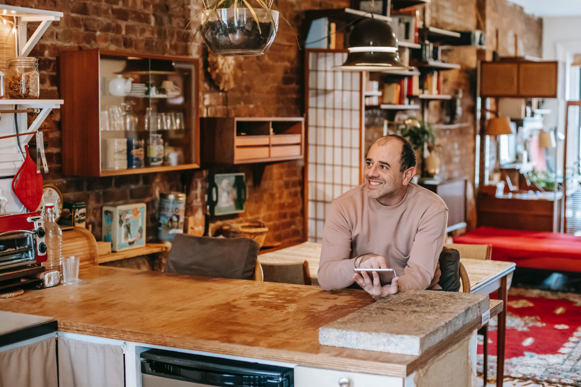 A man smiling while seated by the kitchen counter. | Source: Pexels