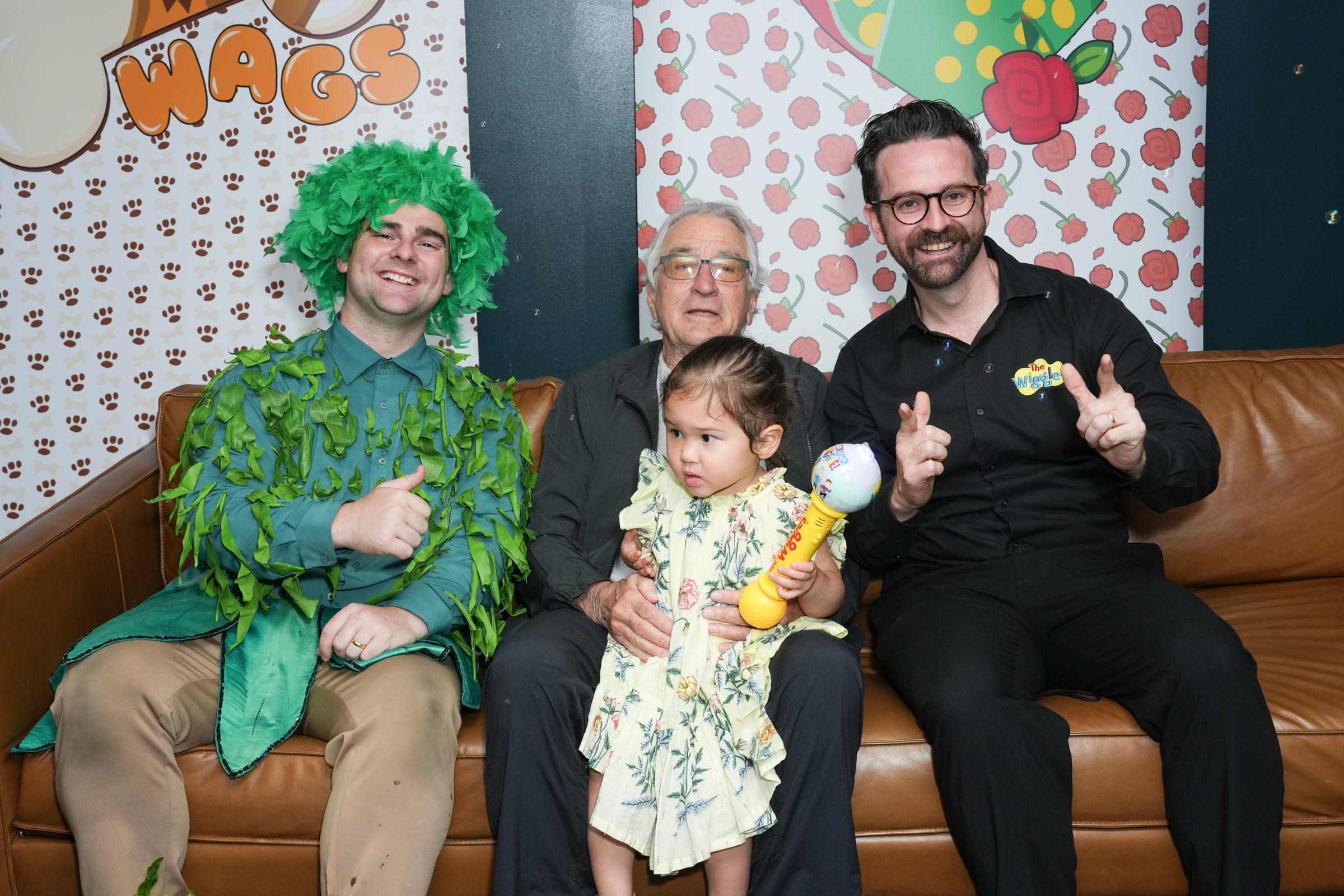 Dominic Field from The Wiggles, dressed in a green costume, poses with Robert De Niro and Gia Virginia Chen-De Niro during the Bouncing Balls Tour stop in New York City | Source: Getty Images