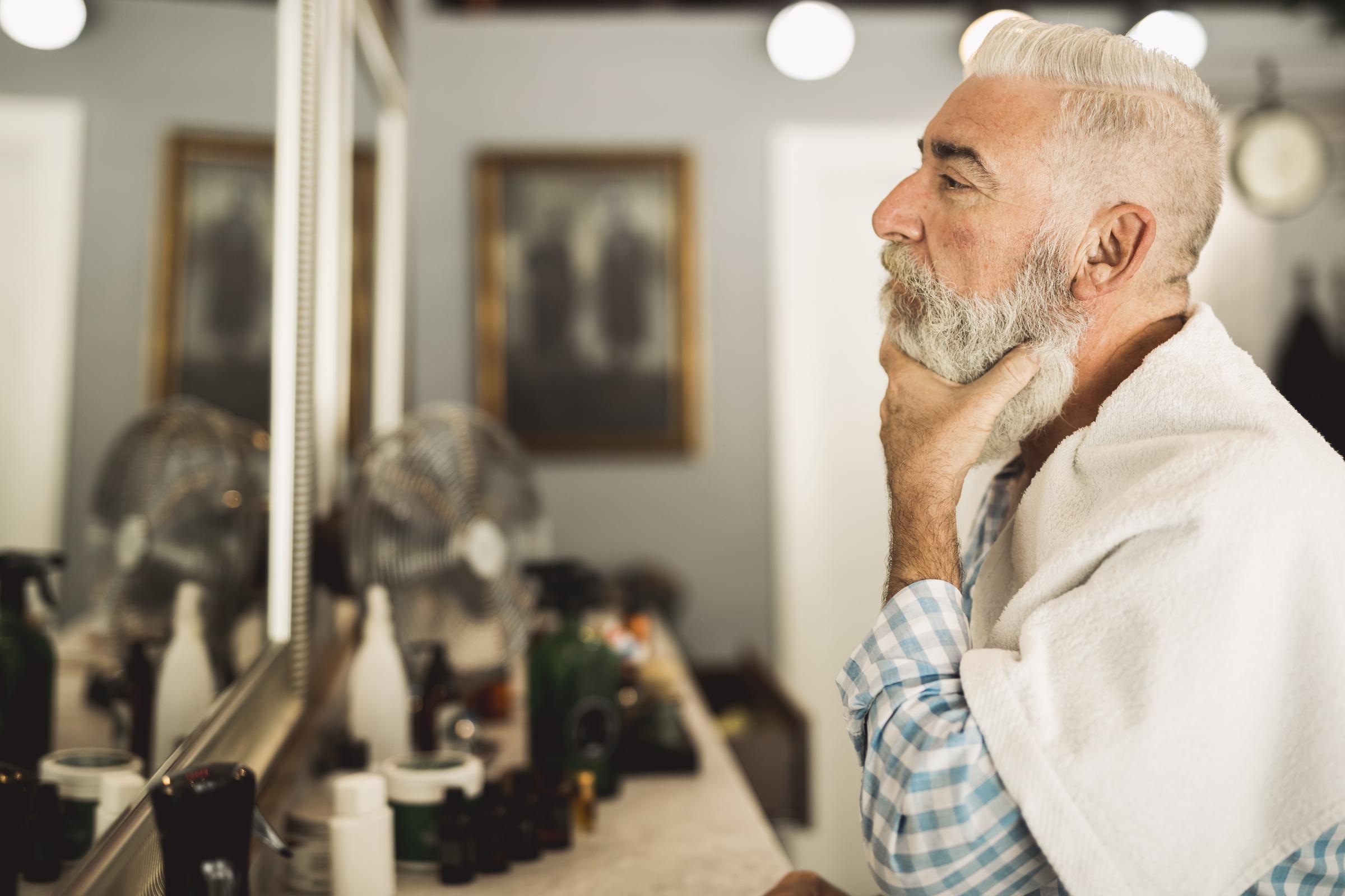 An elderly man looking into a mirror | Source: Freepik