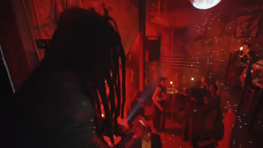 A view from above the crowd captures Lenny standing over the dimly lit dance floor during a basement party. | Source: YouTube/@Archdigest