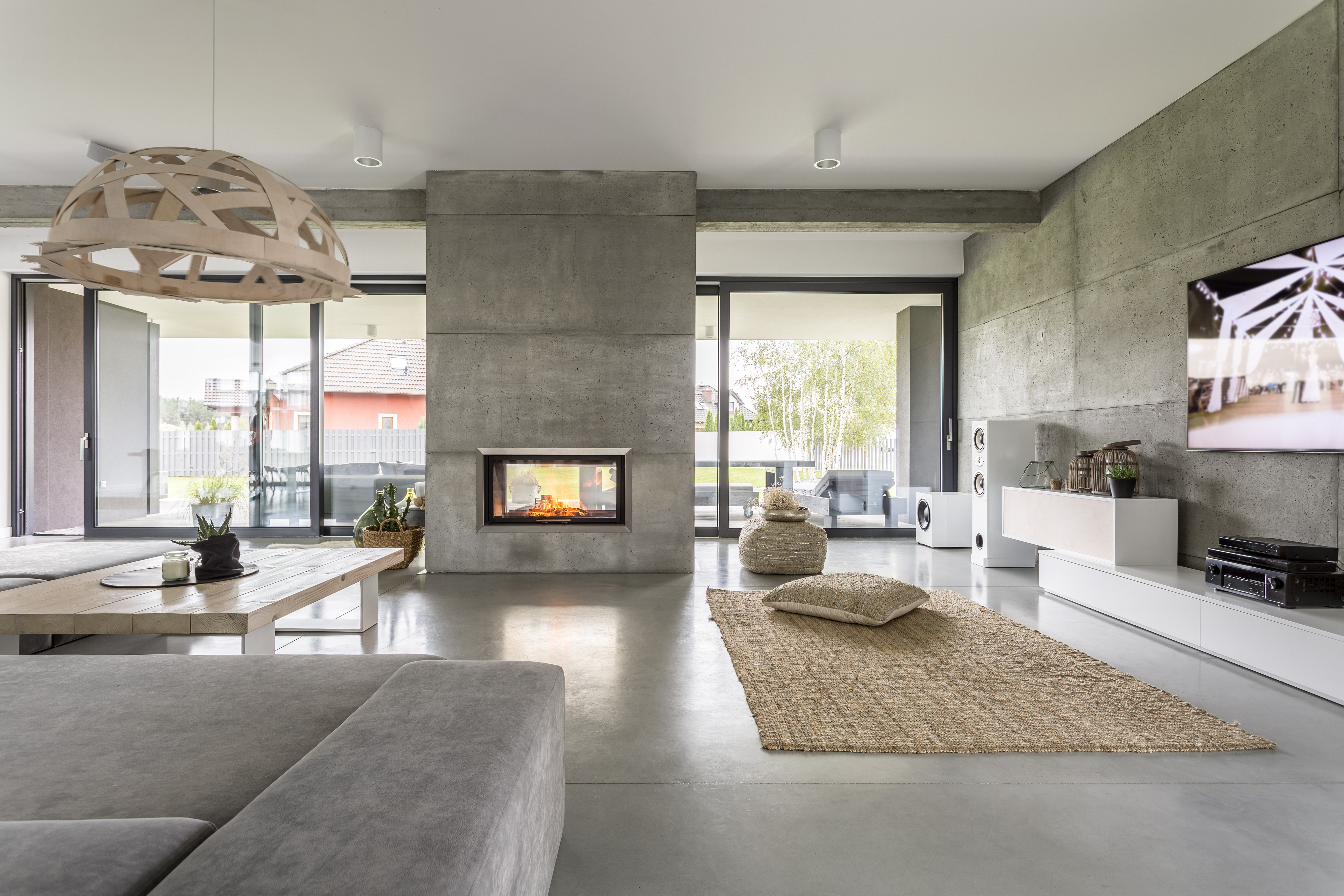 Spacious villa interior with cement wall effect, fireplace and tv.| Source: Shutterstock
