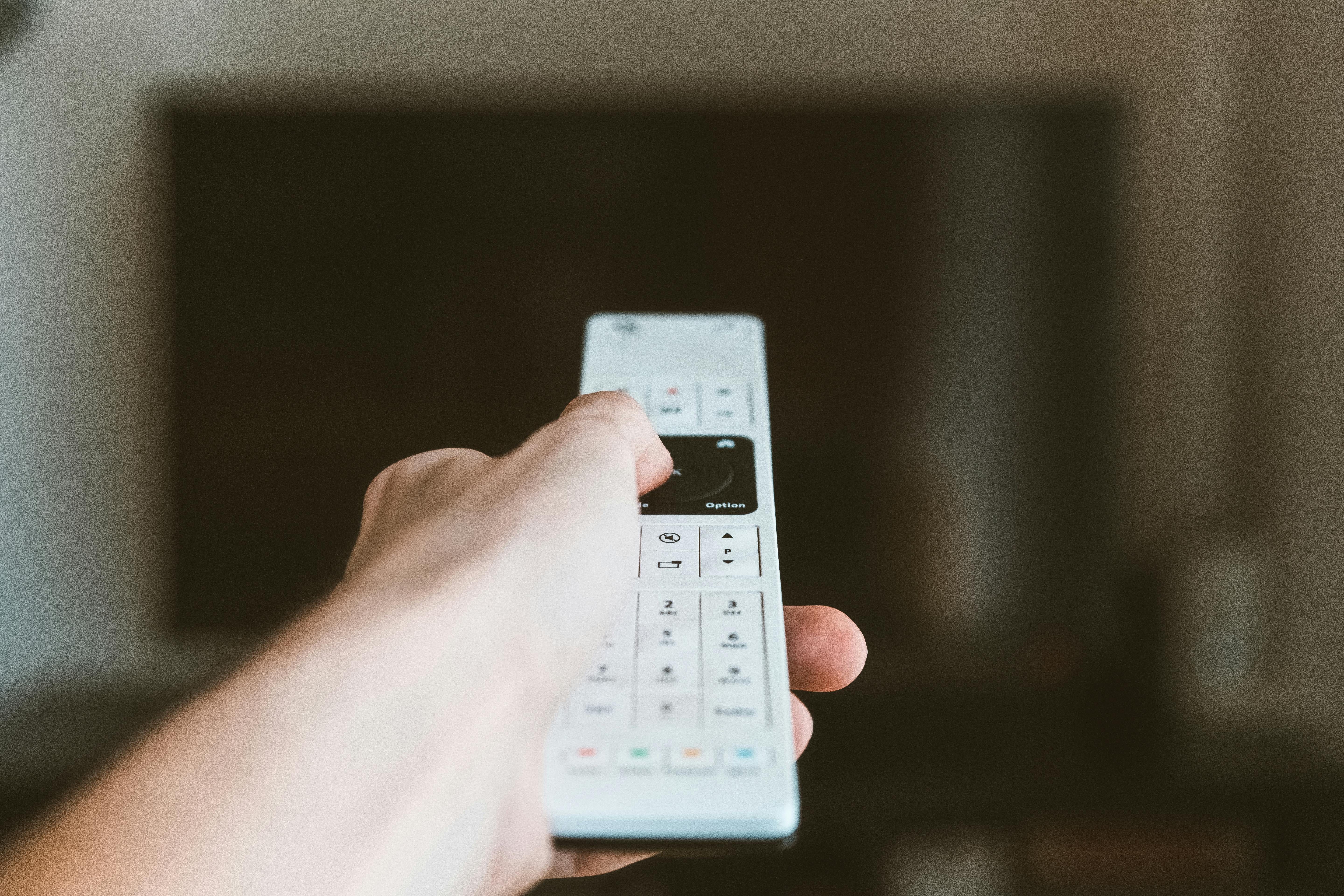 A man's hand holding a TV remote | Source: Pexels