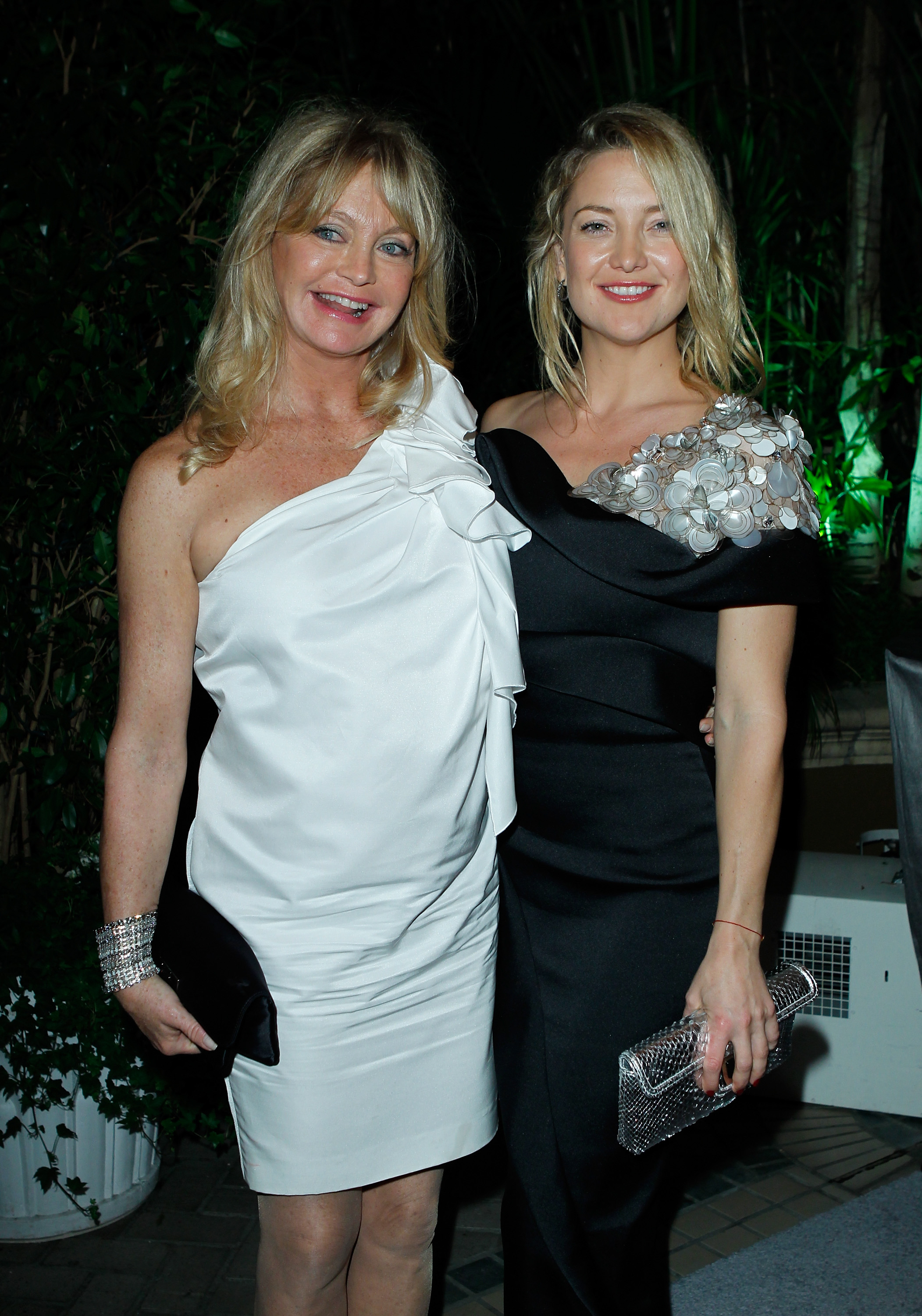 At Elle's Women In Hollywood Tribute, Goldie Hawn supports honoree Kate Hudson. Hawn dazzles in a white one-shoulder dress, while Hudson stuns in an elegant black gown with floral embellishments, reflecting their timeless grace.