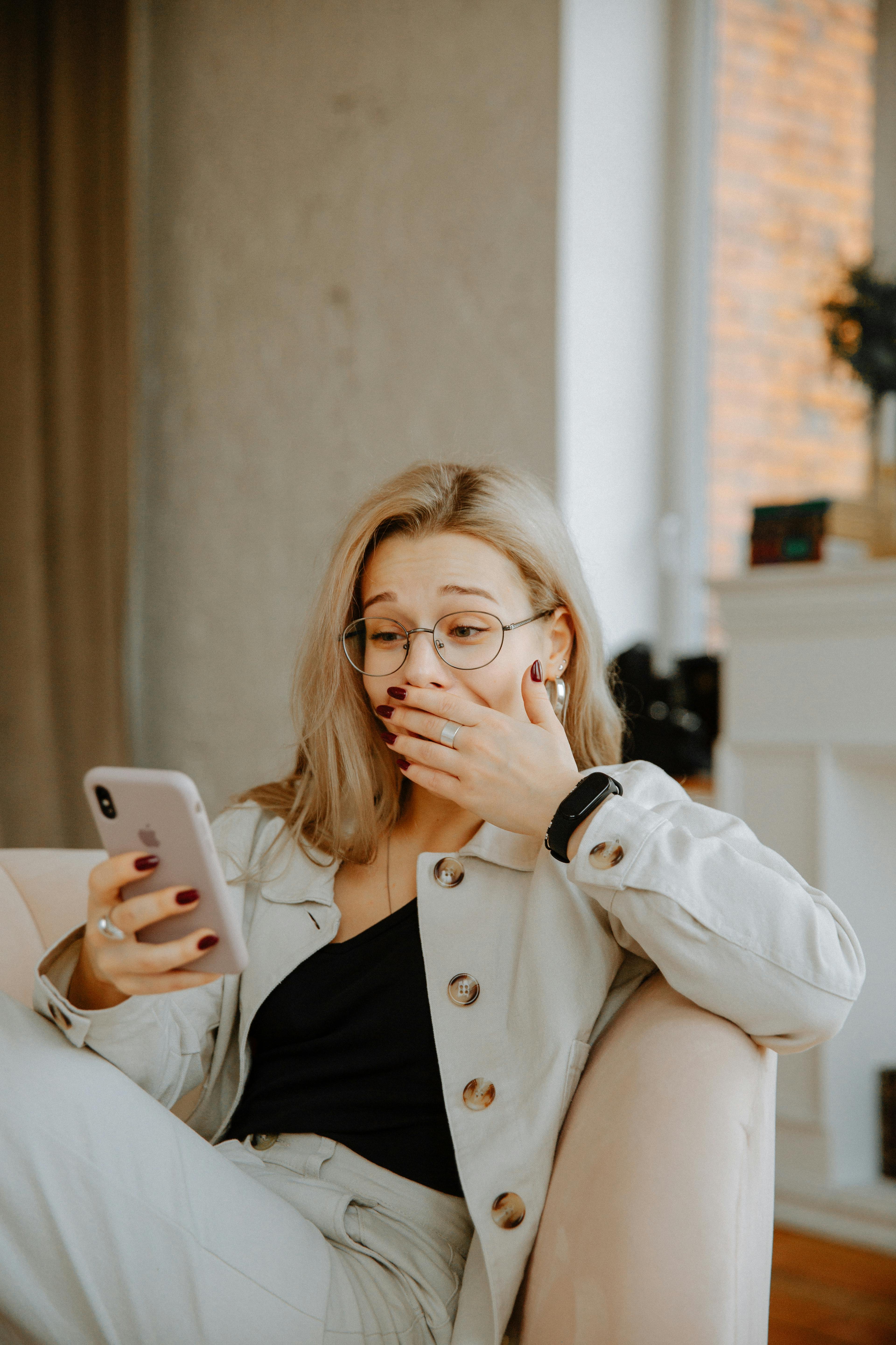 A woman covering her face while looking at her phone | Source: Pexels