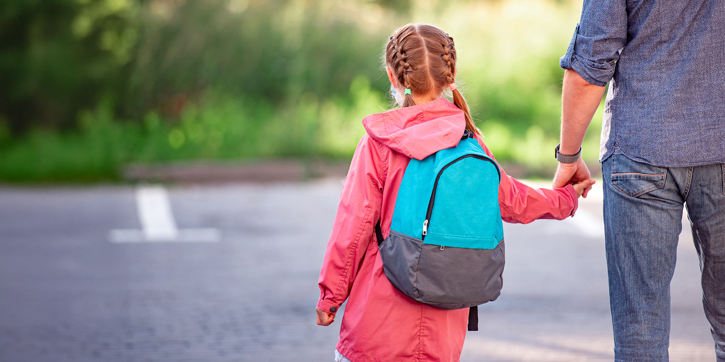 A girl wearing a backpack walking with her father | Source: Shutterstock