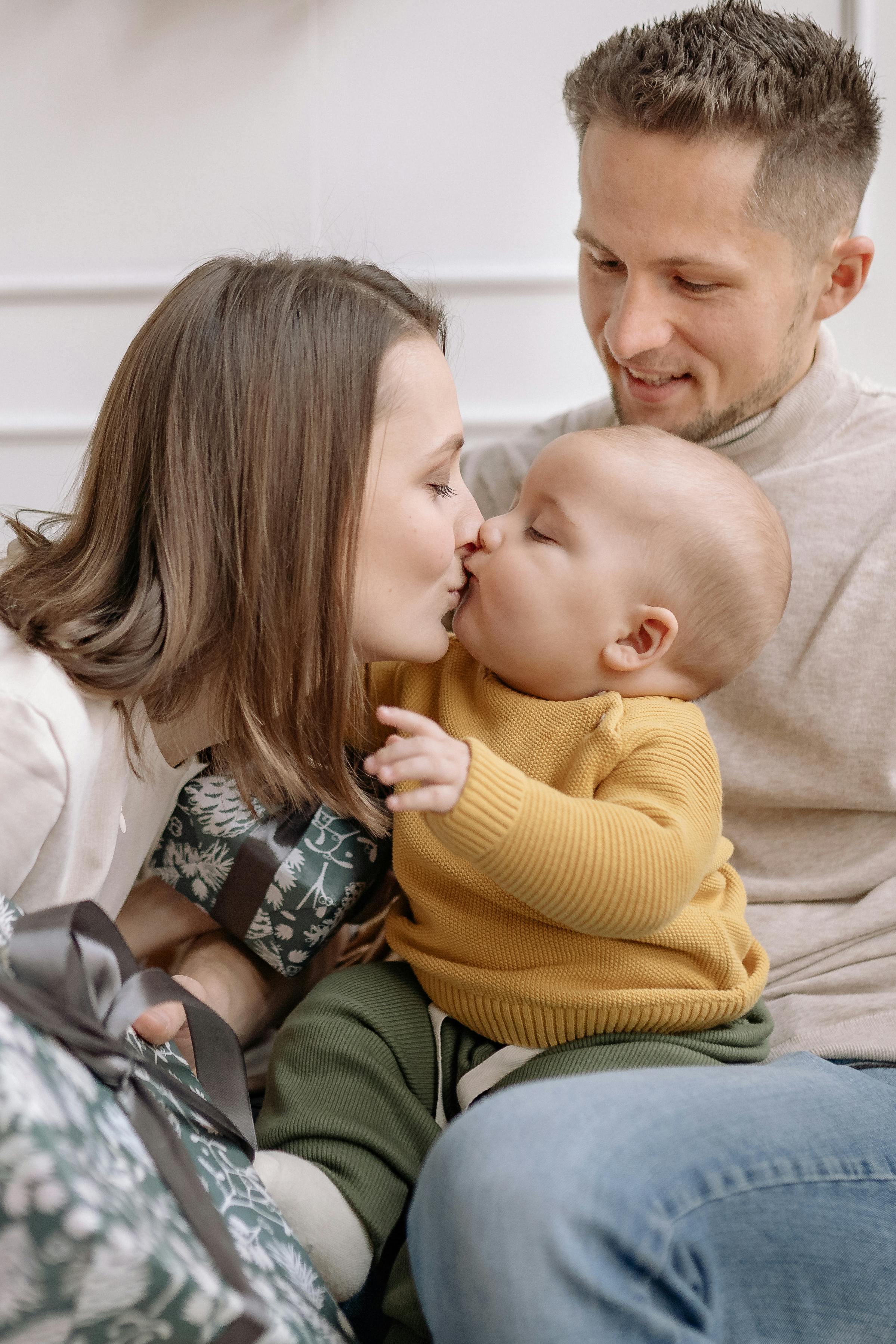 A mother kissing her baby as the father looks on | Source: Pexels